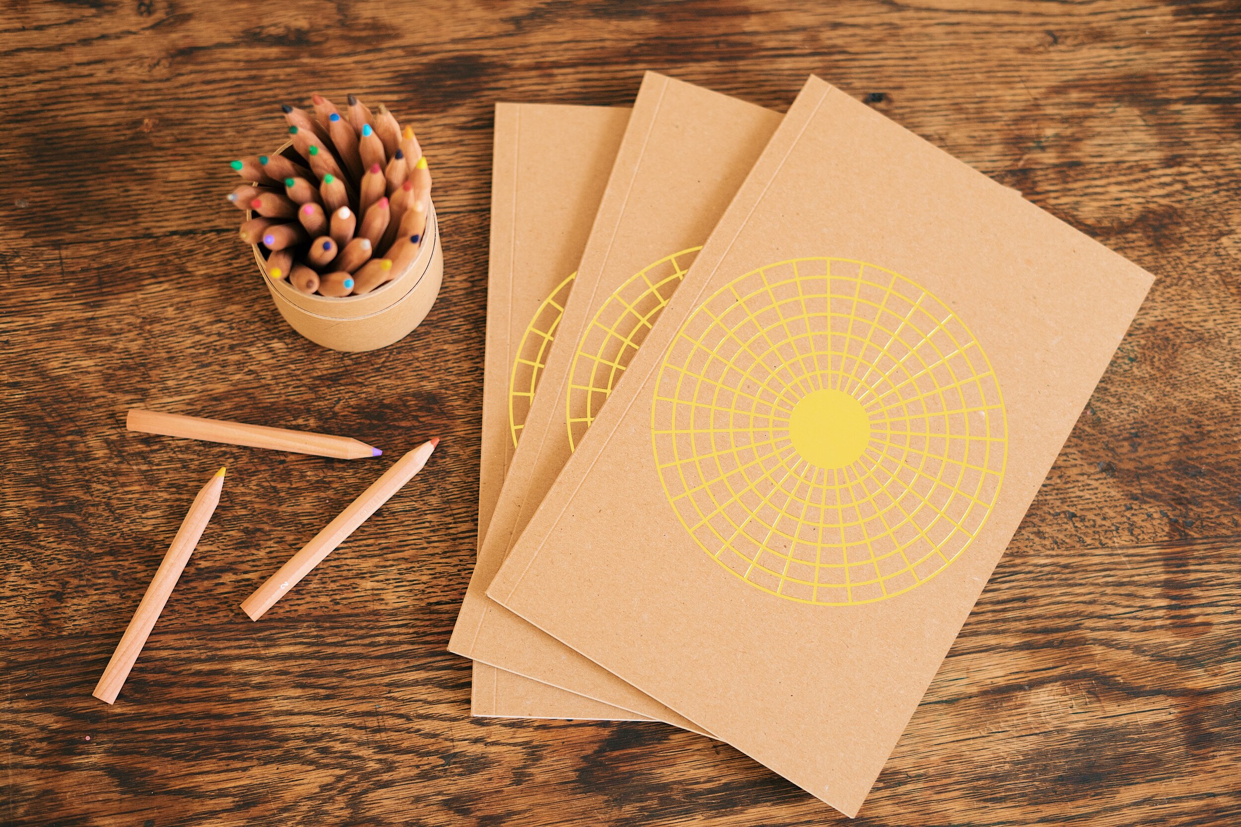 3 journals sitting on table with colored pencils, top down shot. 