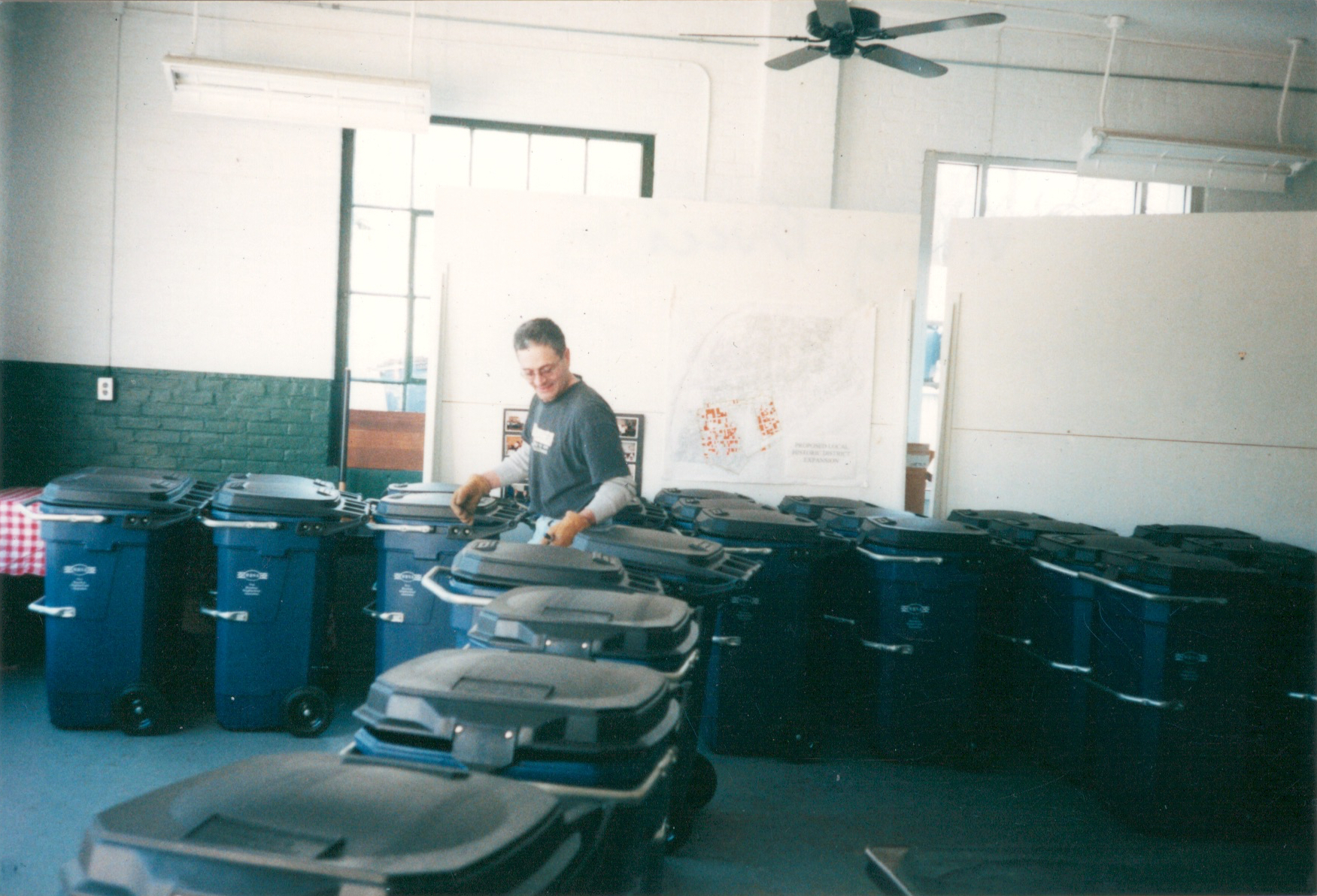 After the first cans were distributed,&nbsp;WBNA applied for United Way and Citizens Bank grants for multiple, successive rounds of bulk trash container purchases. Neighbor Vinny Bucci readies the 45 gallon cans during a pick-up event (2001) 