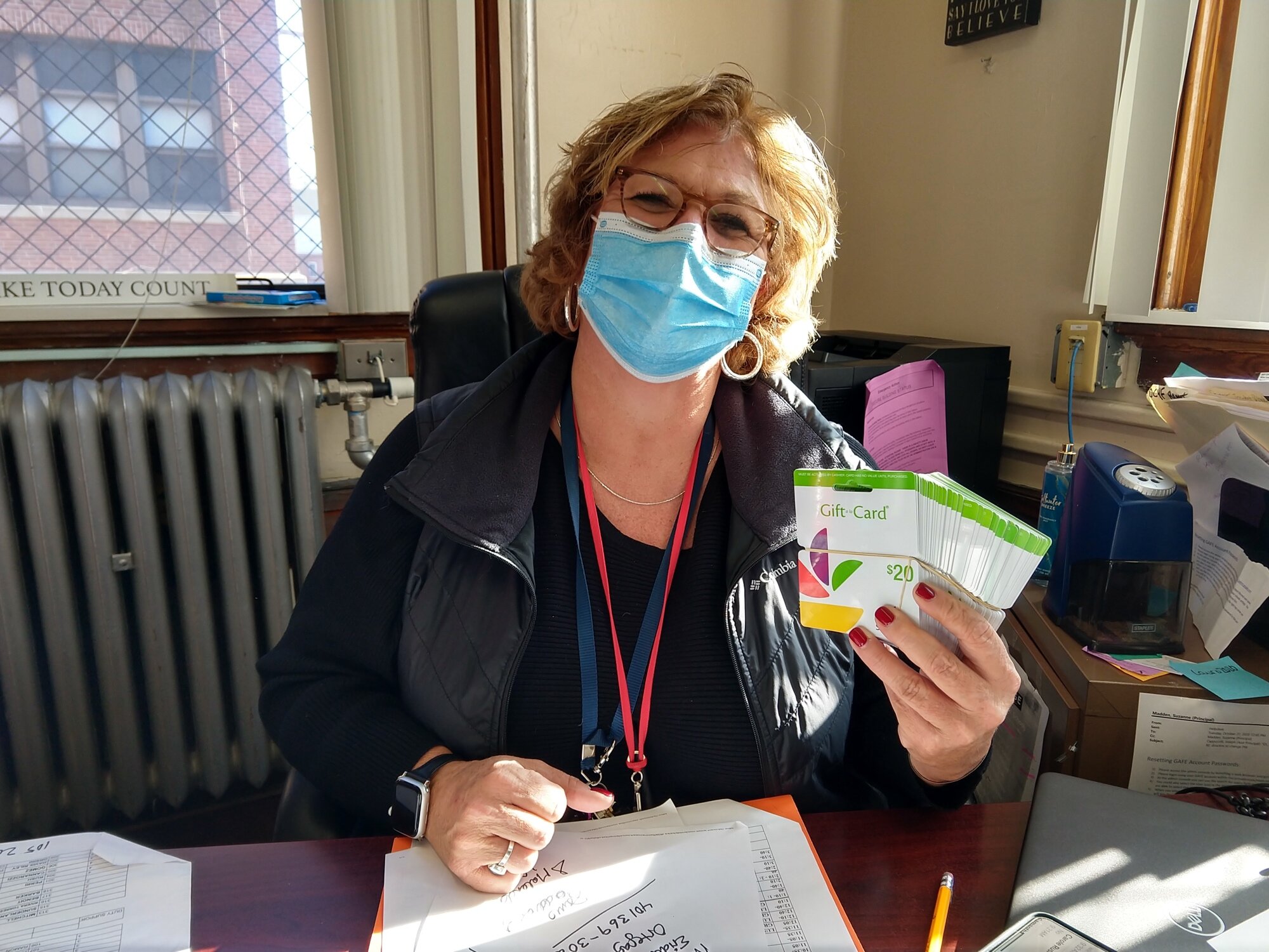  Principal Suzanne Madden of Carl Lauro Elementary School holds a stack of grocery gift cards that were distributed to families at the school 