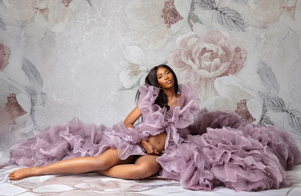 A gorgeous pregnant woman is sitting on the floor posing for her maternity pictures at Barberries Photography Houston studio
