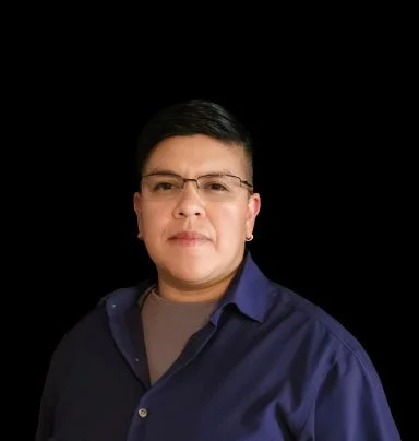 A portrait of a man with short black hair, glasses, wearing a dark blue button-up shirt, against a black background.
