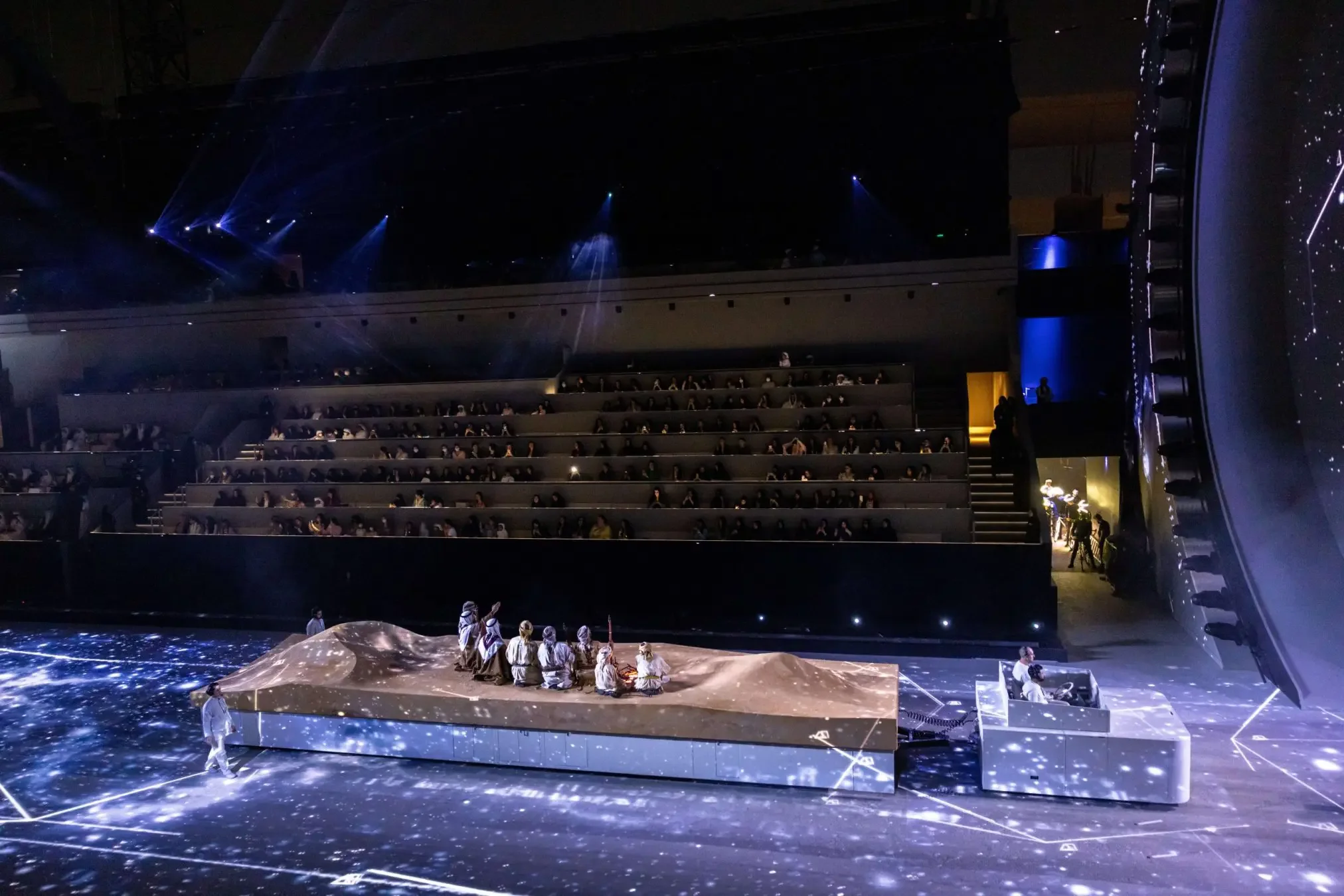 Ceremony stage set in an arena with performers in traditional dress