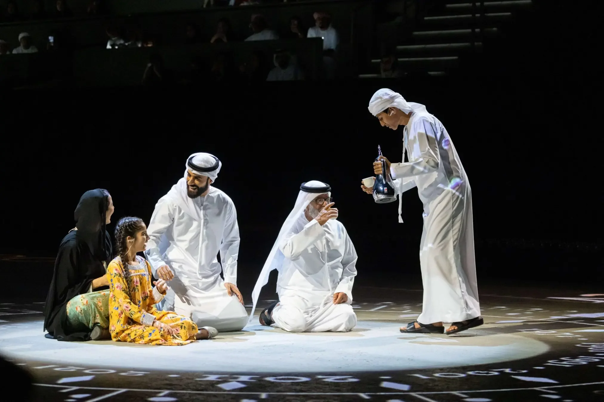 Ceremony performers in traditional Emirati dress on stage