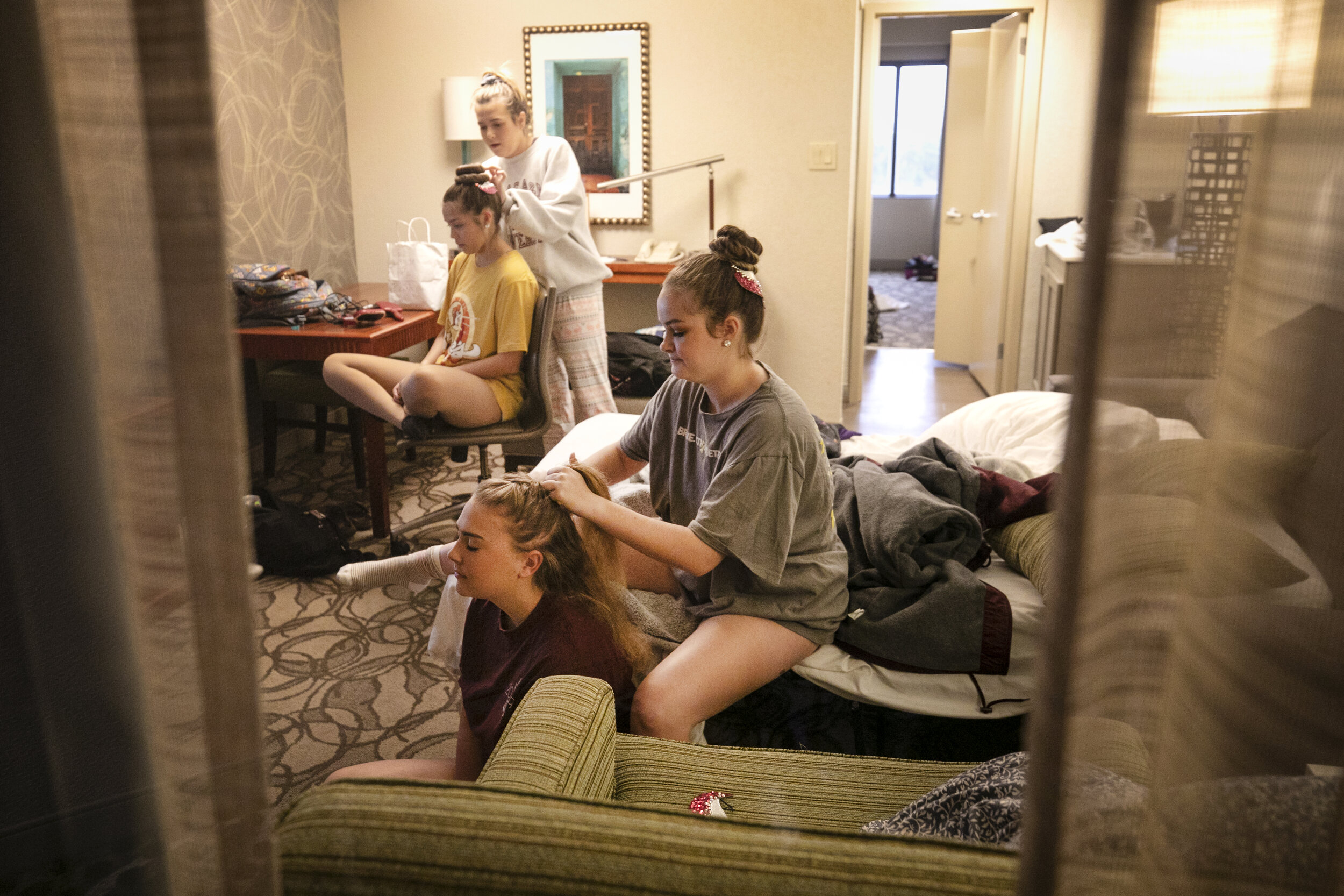  Majorette Kadee Y'Barbo does drum major Katelyn Jester's hair (front right) along with Kylie Pepper and Lizzy Bueno (back left) in their hotel room before leaving for the UIL State Marching Band competition. 