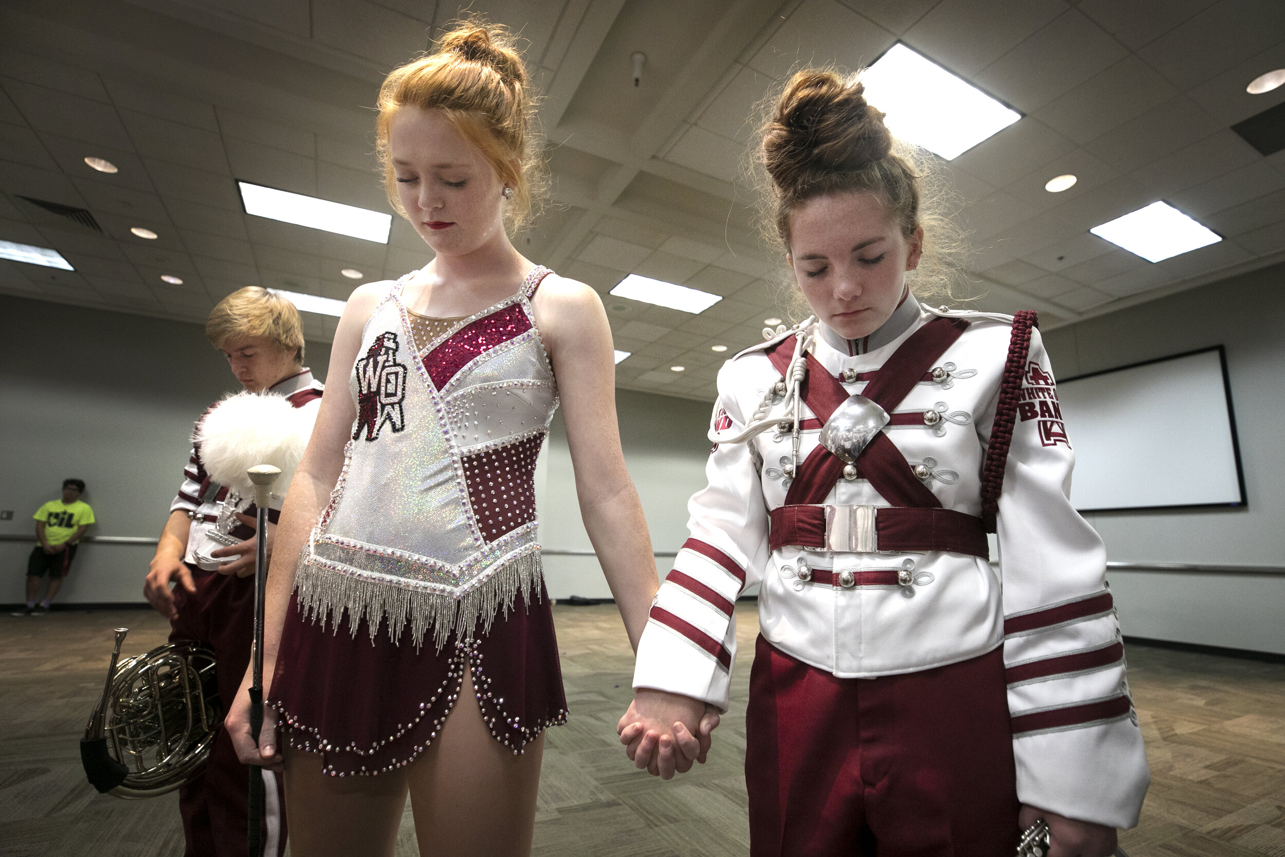  Taylor Gattis (left) and Katelyn Williamson (right) pray with their bandmates before the competition. 
