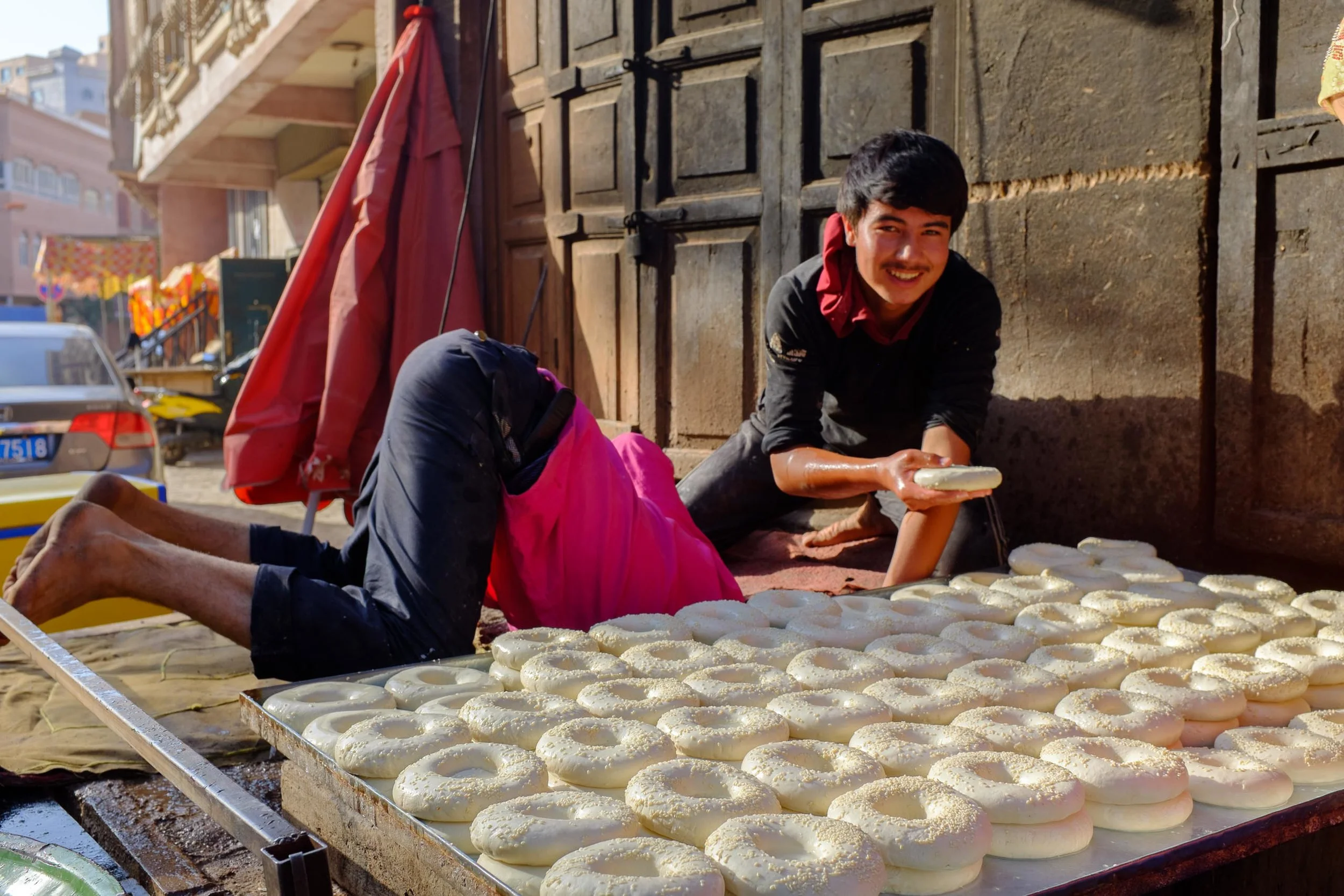 Young men loading a tandoor oven with the days bread
