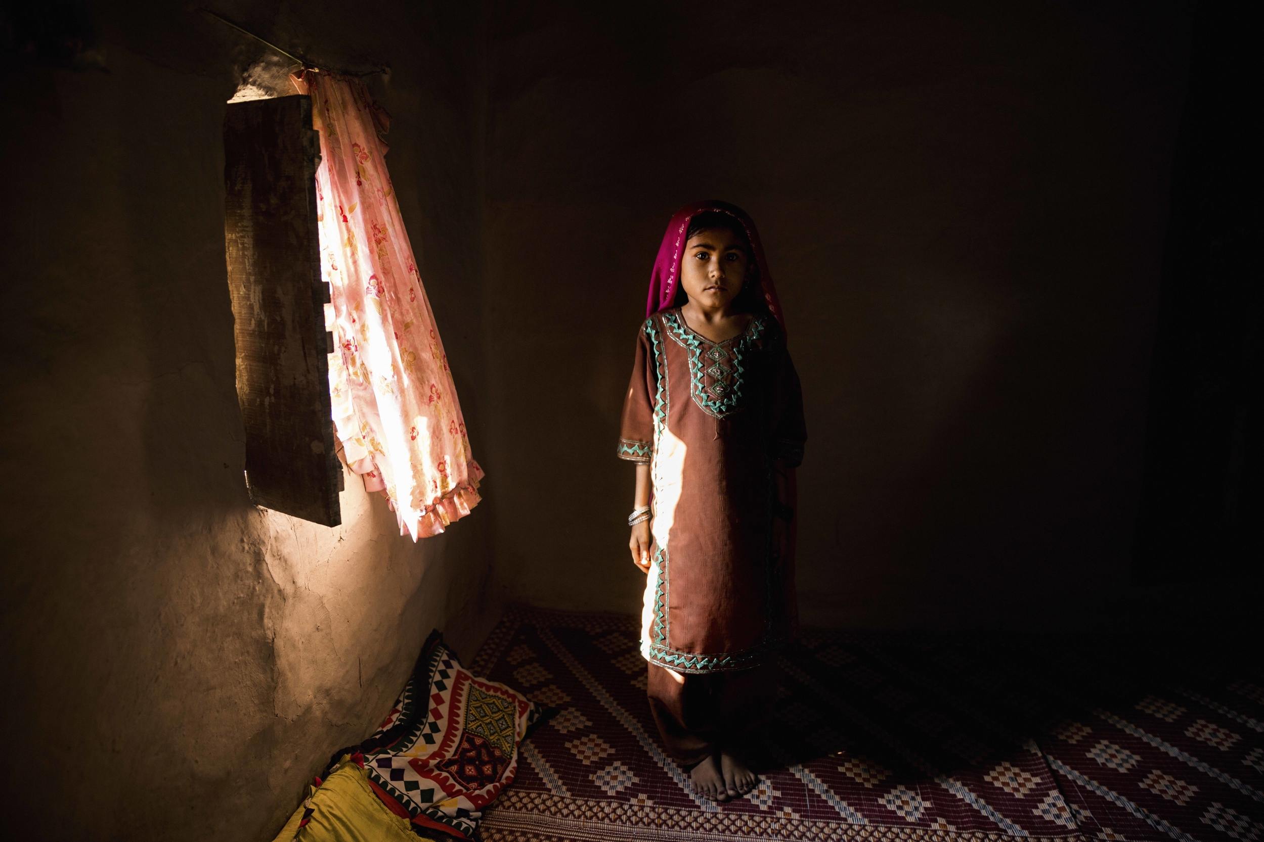 11-year-old Shaneela stands by a window inside her one-room home in Muhammad Ali Bhar. Her parents do not allow her to attend school, although she often sneaks into the classroom anyway. Her parents say they will send her to school when there is access to water and a separate functioning toilet for girls.