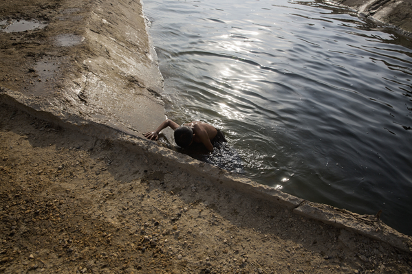A boy climbs out of the canal after a swim in Noor Muhammad Thaheem. The canal is the only source of non-saline water accessible to villagers for their homes. This untreated water is used for bathing as well as cooking and drinking.