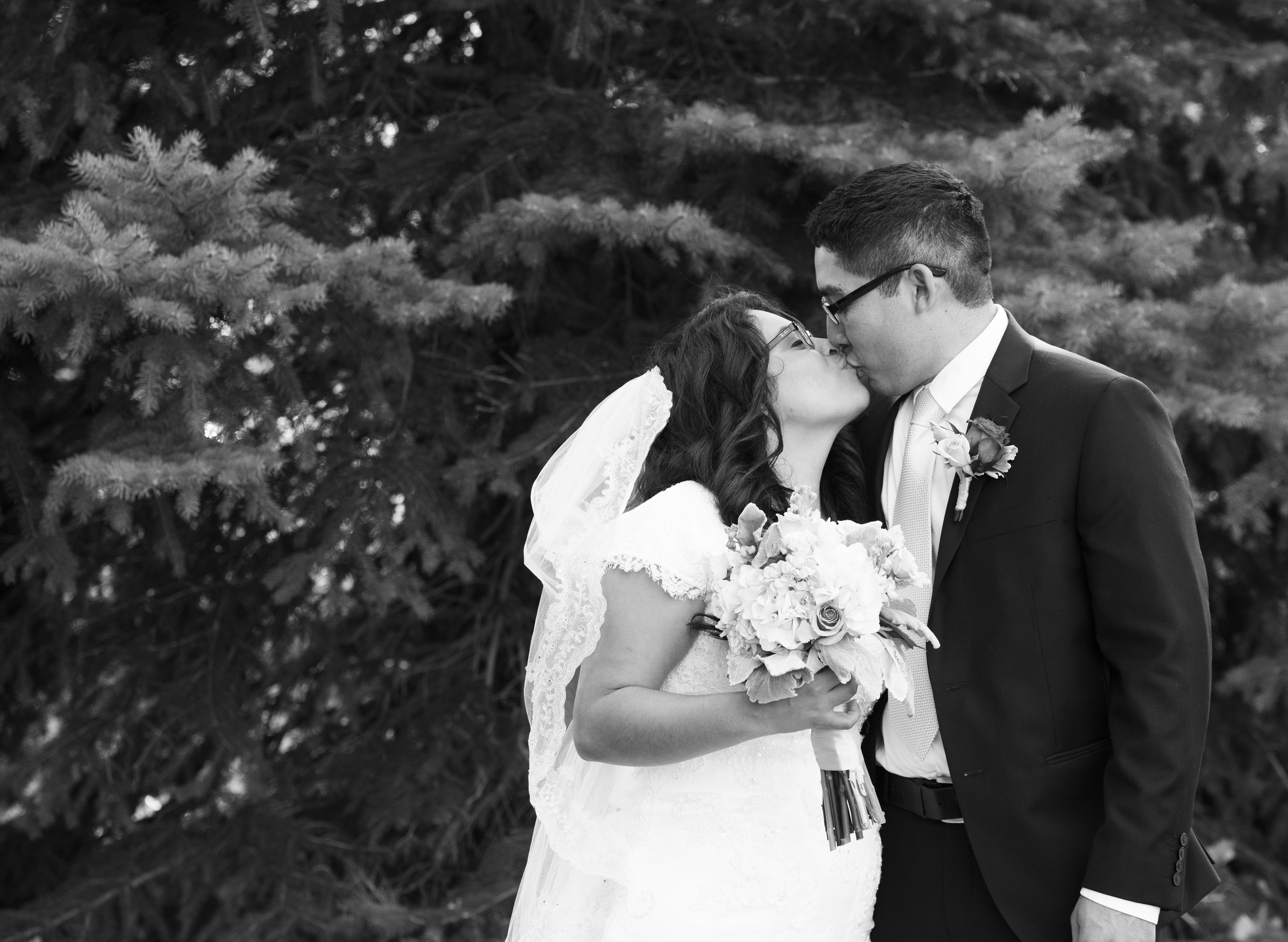 Black and White Photo of the Bride and Groom kissing in profile while the bride holds her bouquet.  Timpanogos Utah Copyright 2016 InTheLoupePhotography