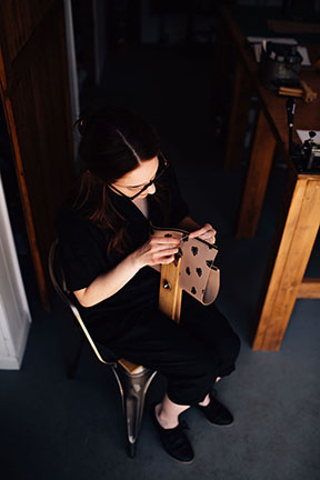 Megan saddle stitching a leather bag in the Stitch &amp; Shutter Studio 