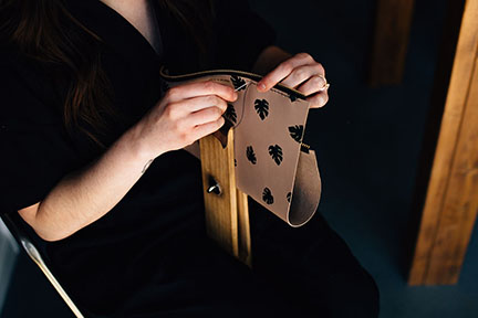 Megan hand stitching a leather bag in the Stitch &amp; Shutter Studio 