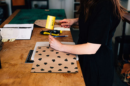 Megan hand punching a leather bag in the Stitch &amp; Shutter Studio 