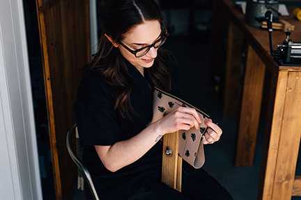 Megan hand stitching a leather bag in the Stitch &amp; Shutter Studio 