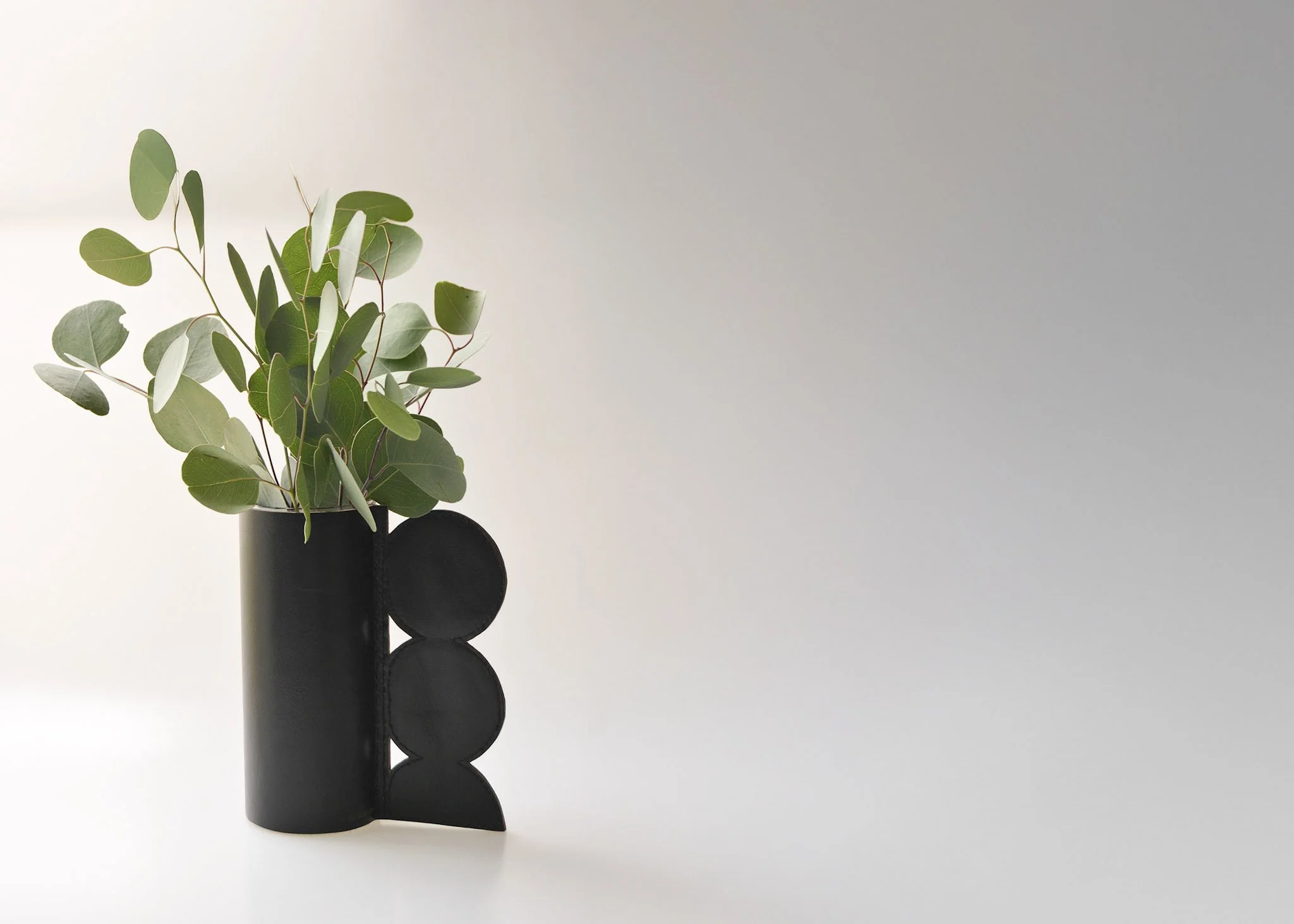 black leather circle handle vase with eucalyptus