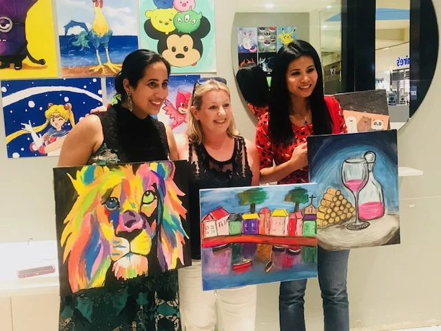 Image of women holding their paintings.