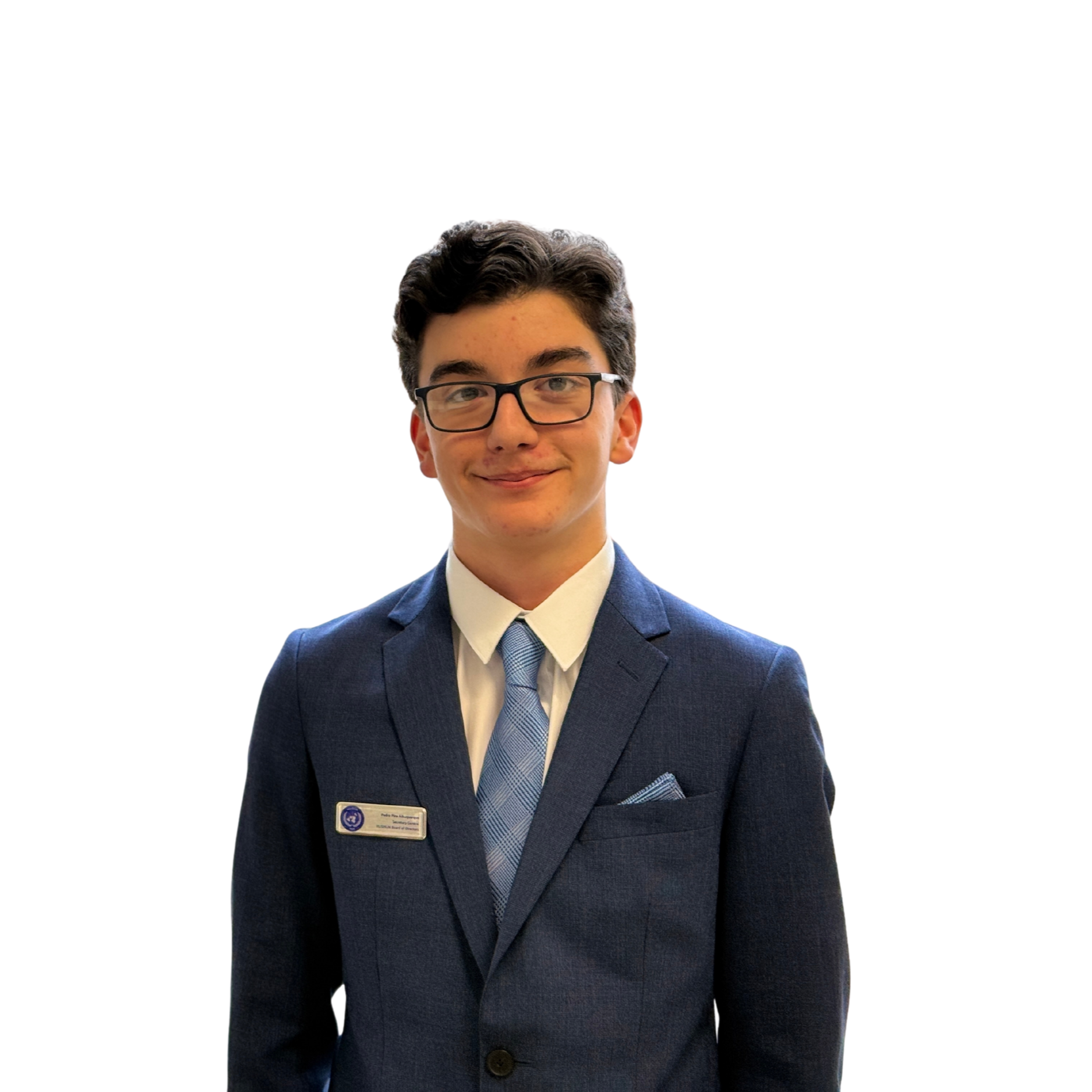 A young man in a navy blue suit, light blue striped tie, white shirt, wearing glasses, with dark wavy hair, smiling, standing against a plain white background, with a name tag on his suit.