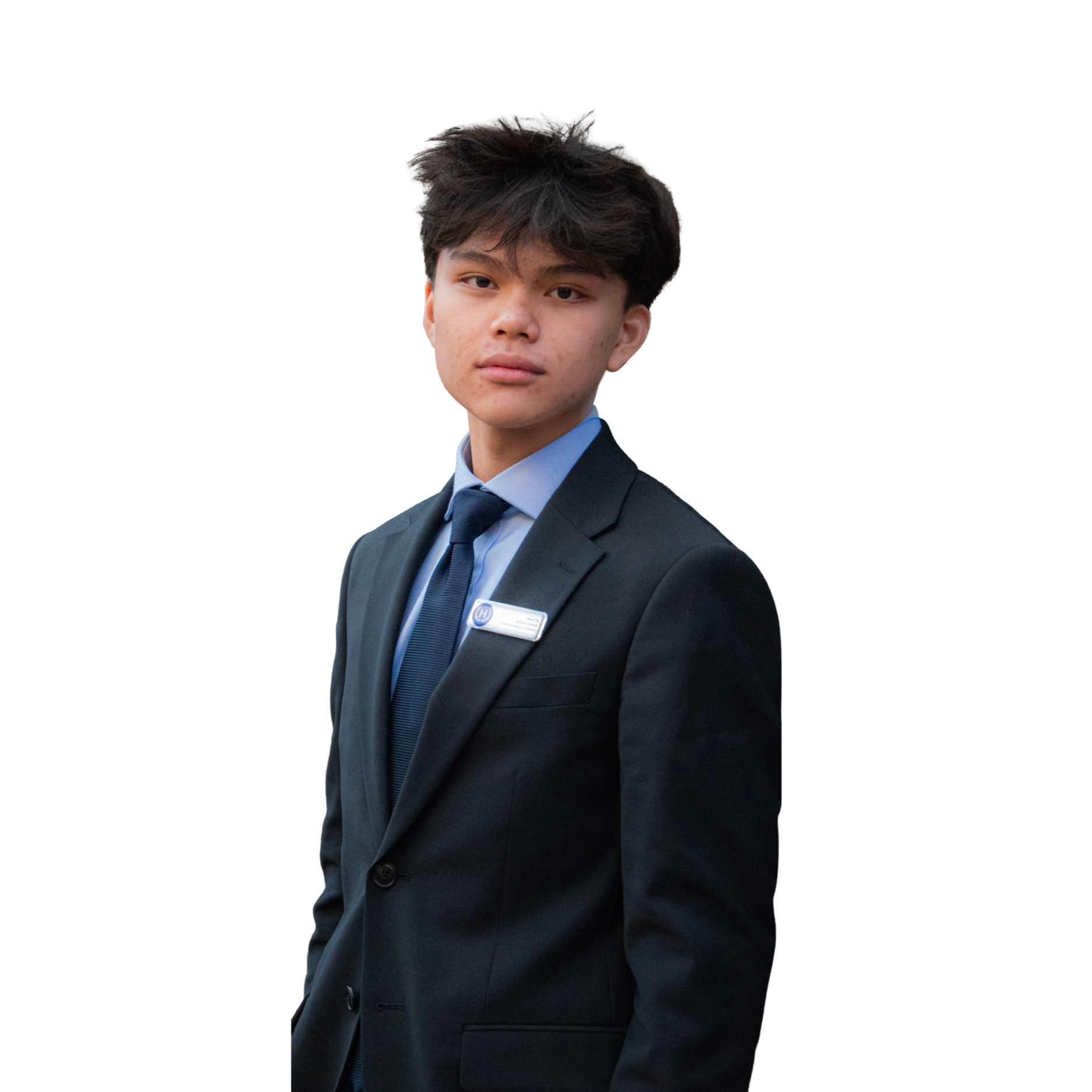 Young man with dark hair wearing a navy blazer, light blue dress shirt, and dark tie, standing against a plain white background.