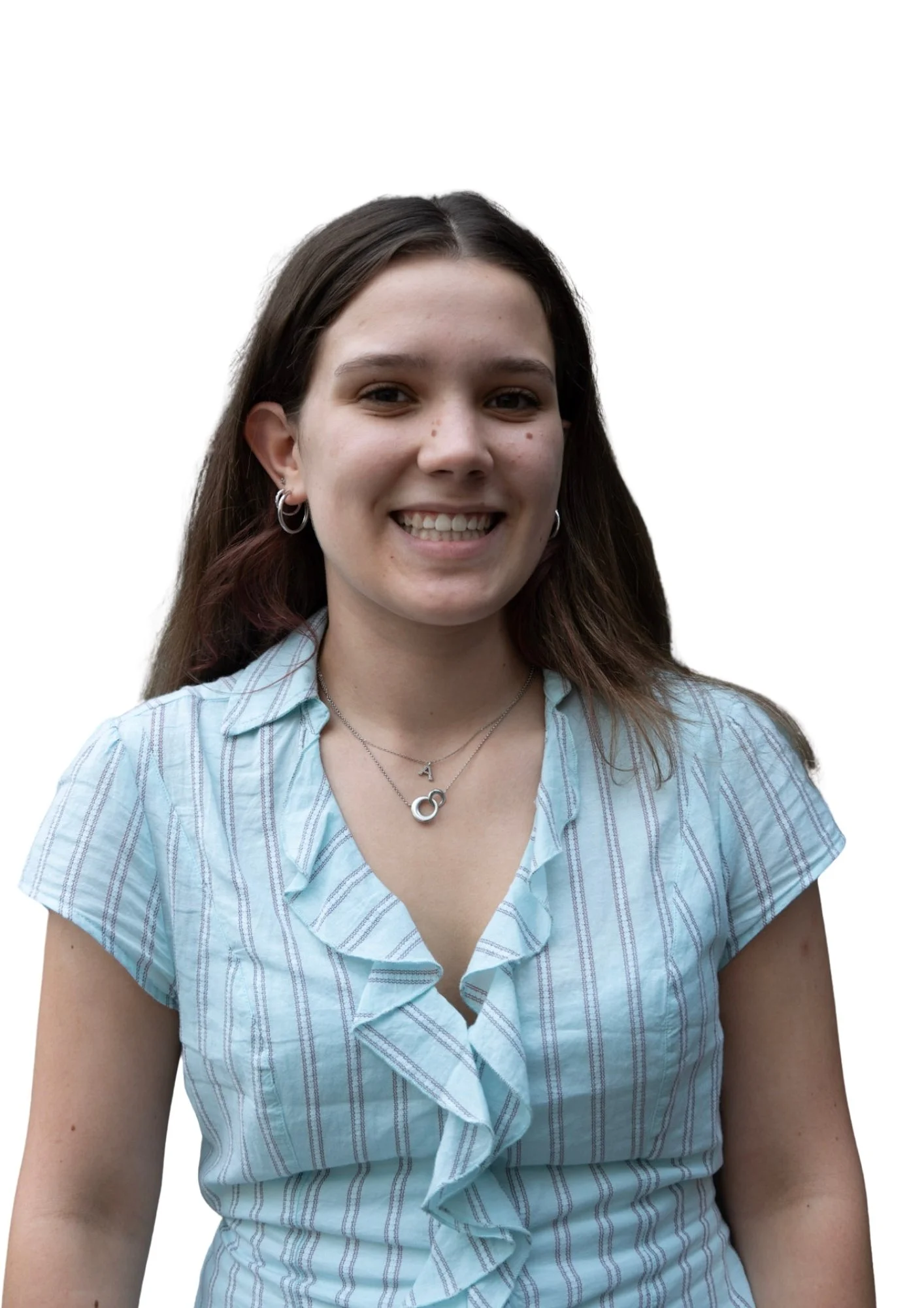 Close-up of a smiling young woman with brown hair, earrings, and layered necklaces, wearing a light blue striped blouse with ruffle details.