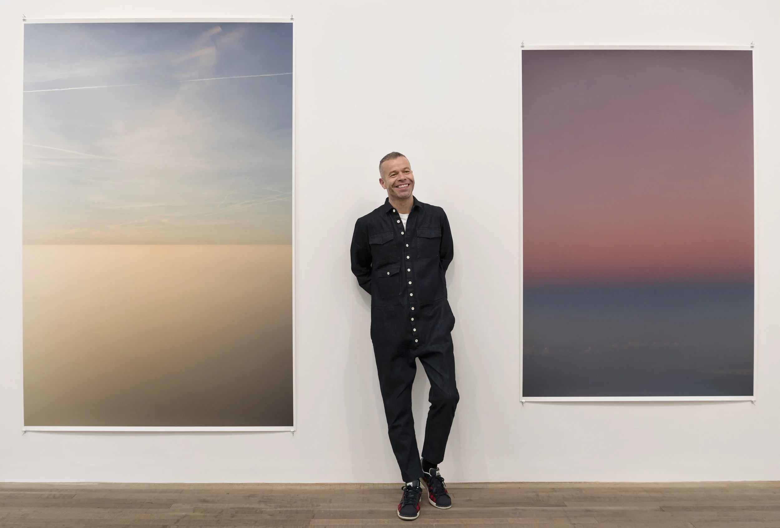 Wolfgang Tillmans poses in front of his works Transient 2, 2015 and Tag/Nacht II, 2010. Courtesy Tate Photography