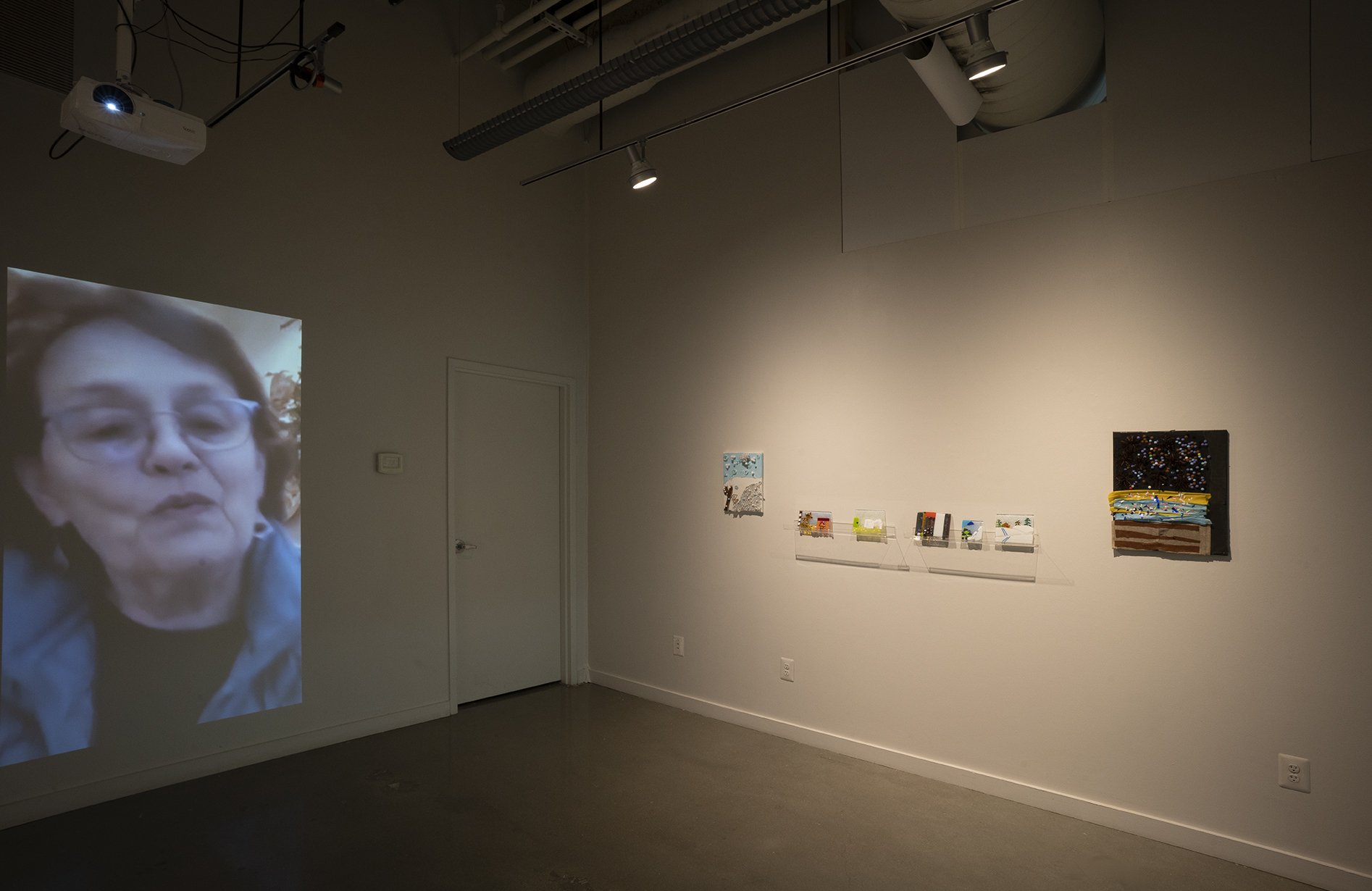  View of exhibition at VisArts, Rockville, MD, 2021, featuring recorded memories from elder adults from area that served as inspiration for children in fused glass and fabric collage workshops. 