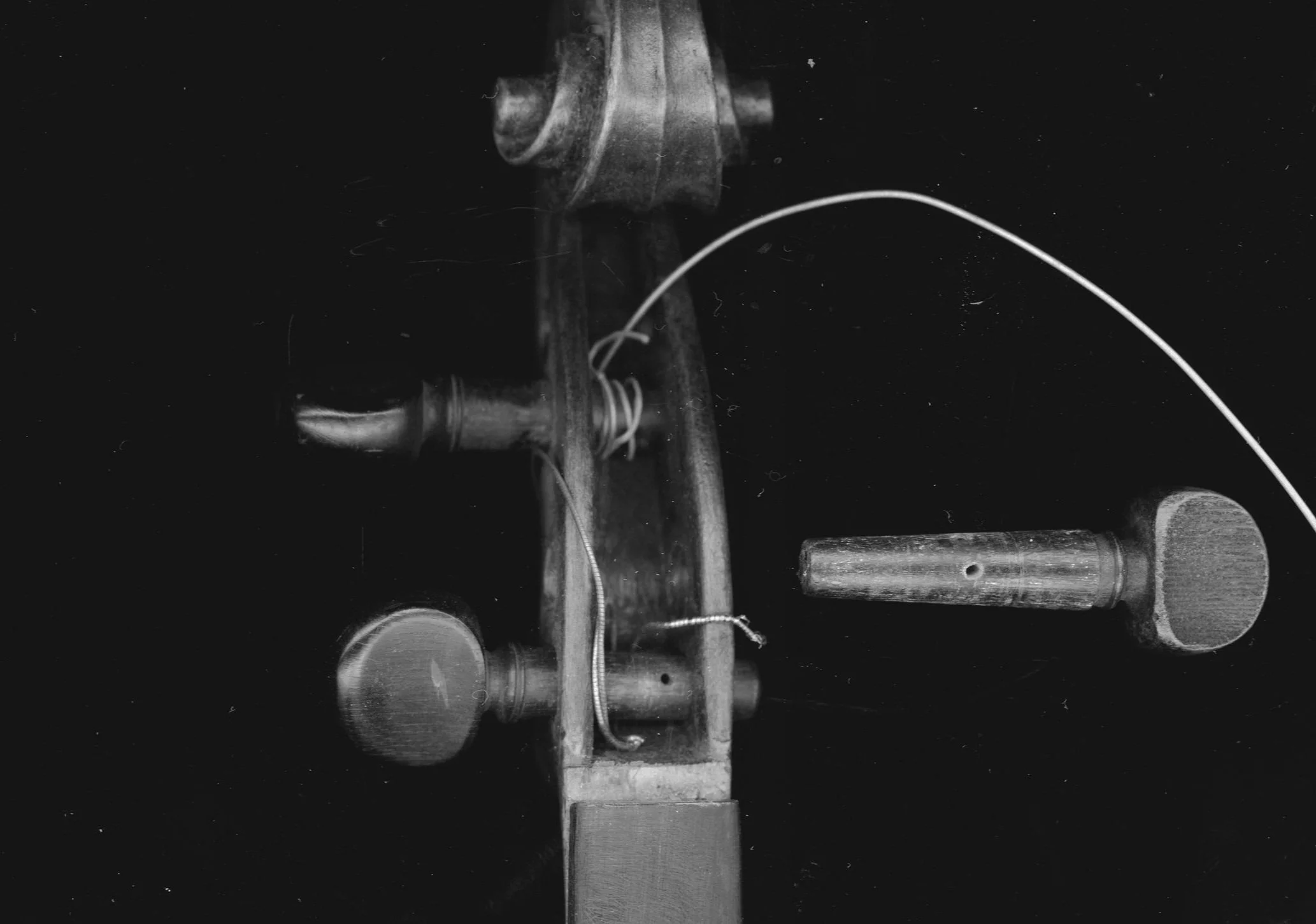 An old-fashioned violin with parts separated and strings visible, placed on a dark surface.