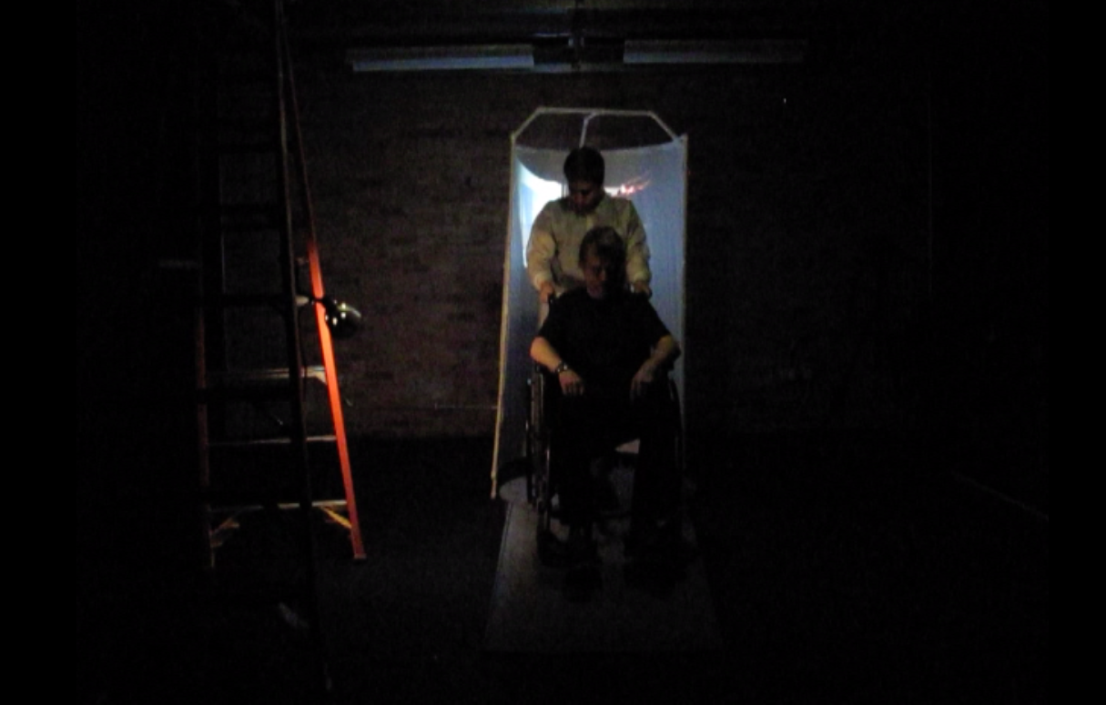A script was written that would be read during the performance (portions of the script were also used in SKYPE Conversation #2 ). Setting: in a darkened space, the performer, seated in a wheelchair, is wheeled into the space and pulled up a ramp by an assistant (an orderly) wearing a white coat. 