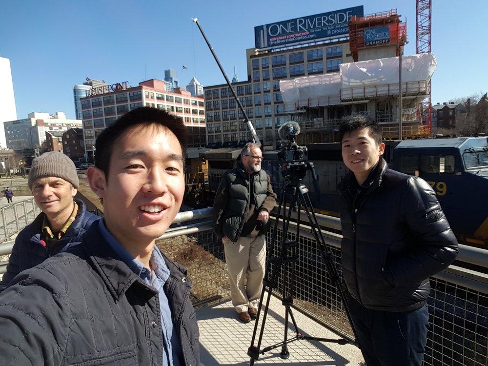 Ben Kalina, Chris Kao, Joe Minott, and Xiaofei Ye pose for a selfie as an oil train chugs by