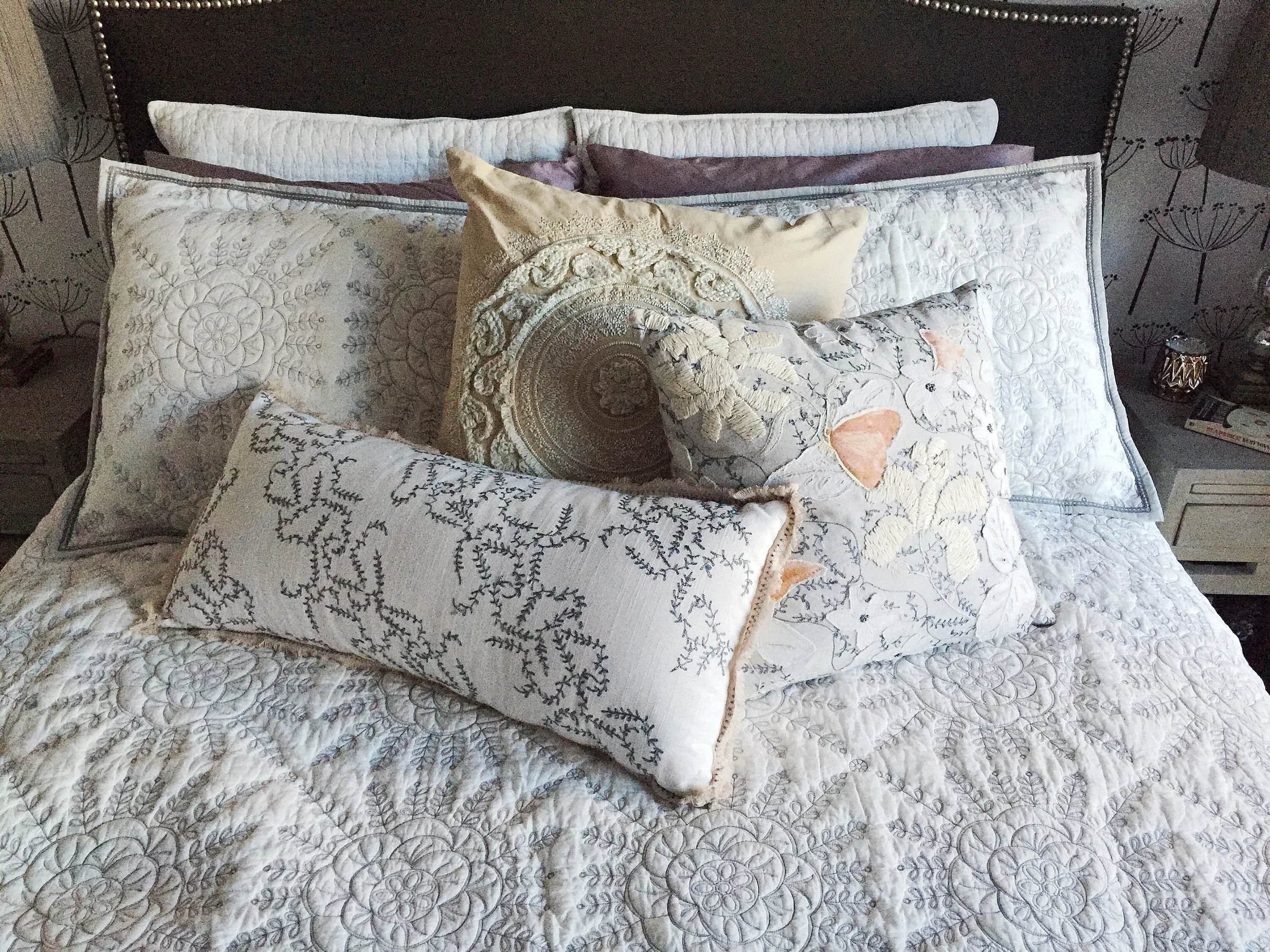  We chose an embroidered quilt and throw pillows for bedding, a pair of new night stands and matching table lamps to round out the accent wall.