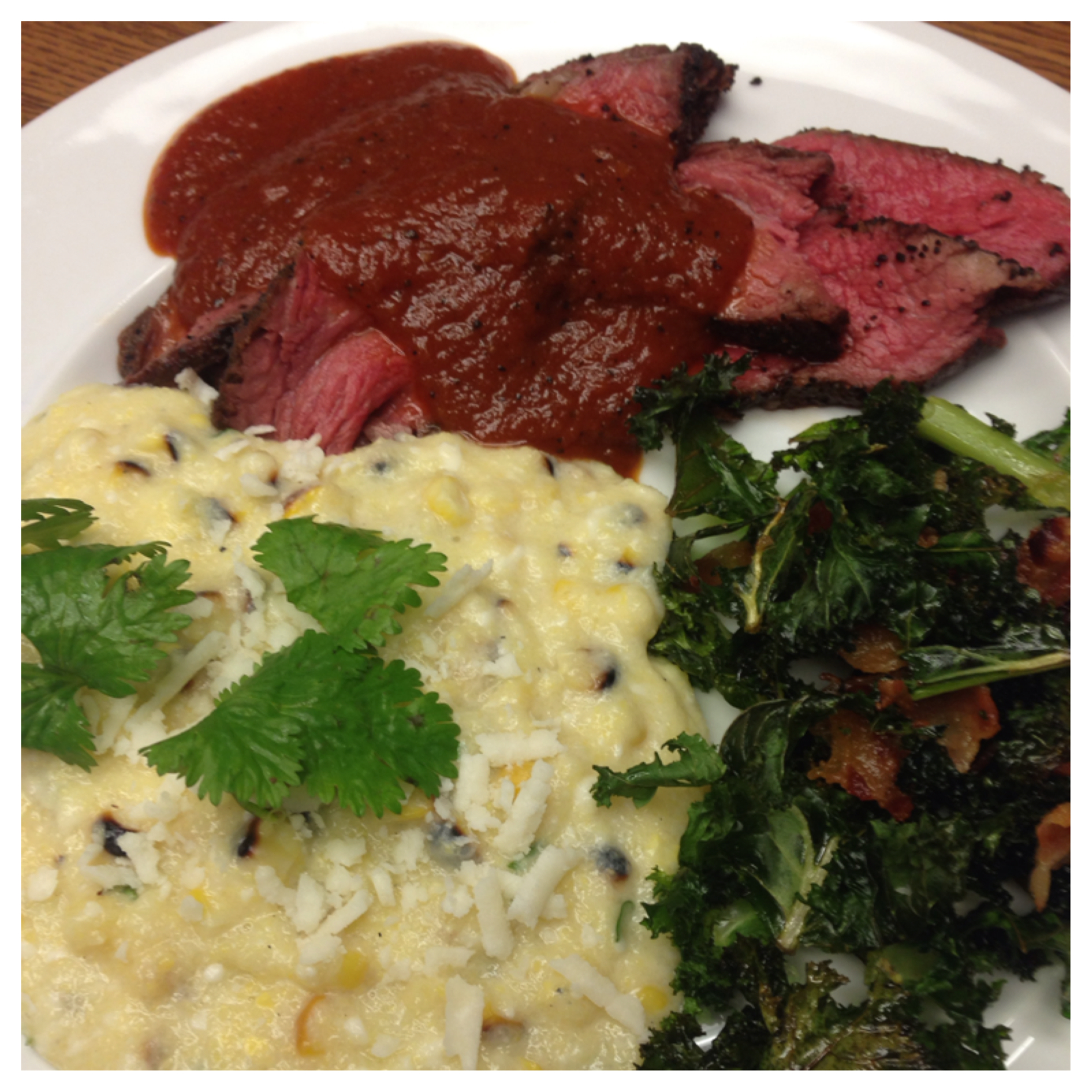 I SERVED THE STEAK WITH A SIDE OF MEXICAN CORN POLENTA AND KALE CHIPS WITH BACON. I TOOK INFLUENCE FROM AMERICAN BARBECUE, MEXICAN AND ITALIAN CUISINES. THE POLENTA HAS COCONUT MILK FOR SWEETNESS, ROASTED CORN, CILANTRO, LIME JUICE AND COTIJA CHEESE, ALL THE FLAVORS OF THE POPULAR MEXICAN STREET FOOD. THE KALE IS A PLAY ON SOUTHERN GREENS THAT ARE USUALLY MADE WITH COLLARDS. I WANTED A CRUNCHY TEXTURE IN THE DISH SO I MADE THEM INTO CHIPS AND ADDED BACON INSTEAD OF THE SMOKED HAM HOCK WHICH IS TYPICALLY FOUND IN GREENS.