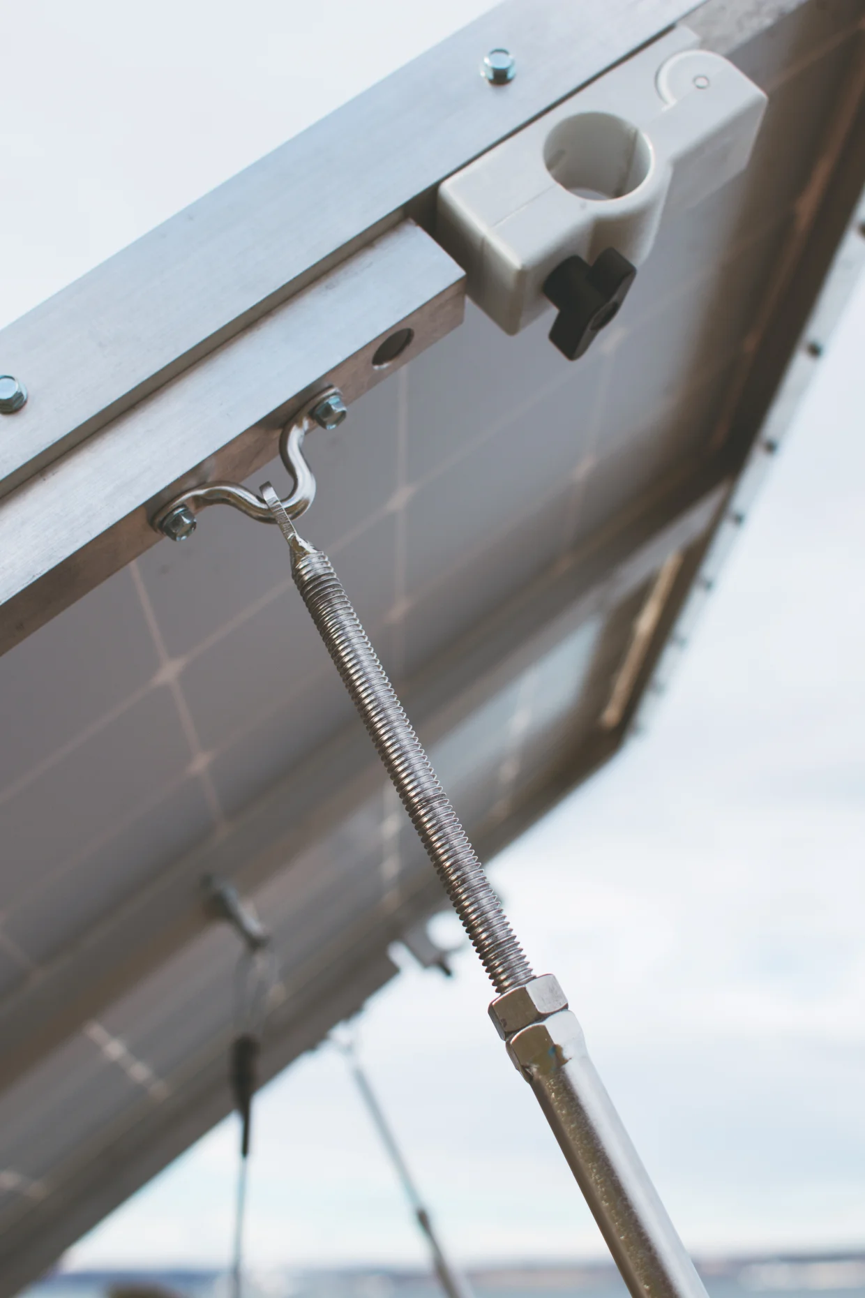 The white clip in this photo is the locking mechanism for the system. When the black toggle is screwed out, the lock opens and can be clamped over the cross beams on the roof rack.