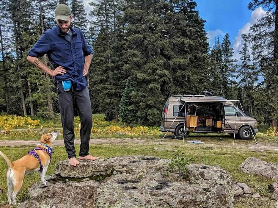 man-stands-on-rock-with-dogs-sniffing-below-him-and-van-in-the-background-1-1024x768.jpg