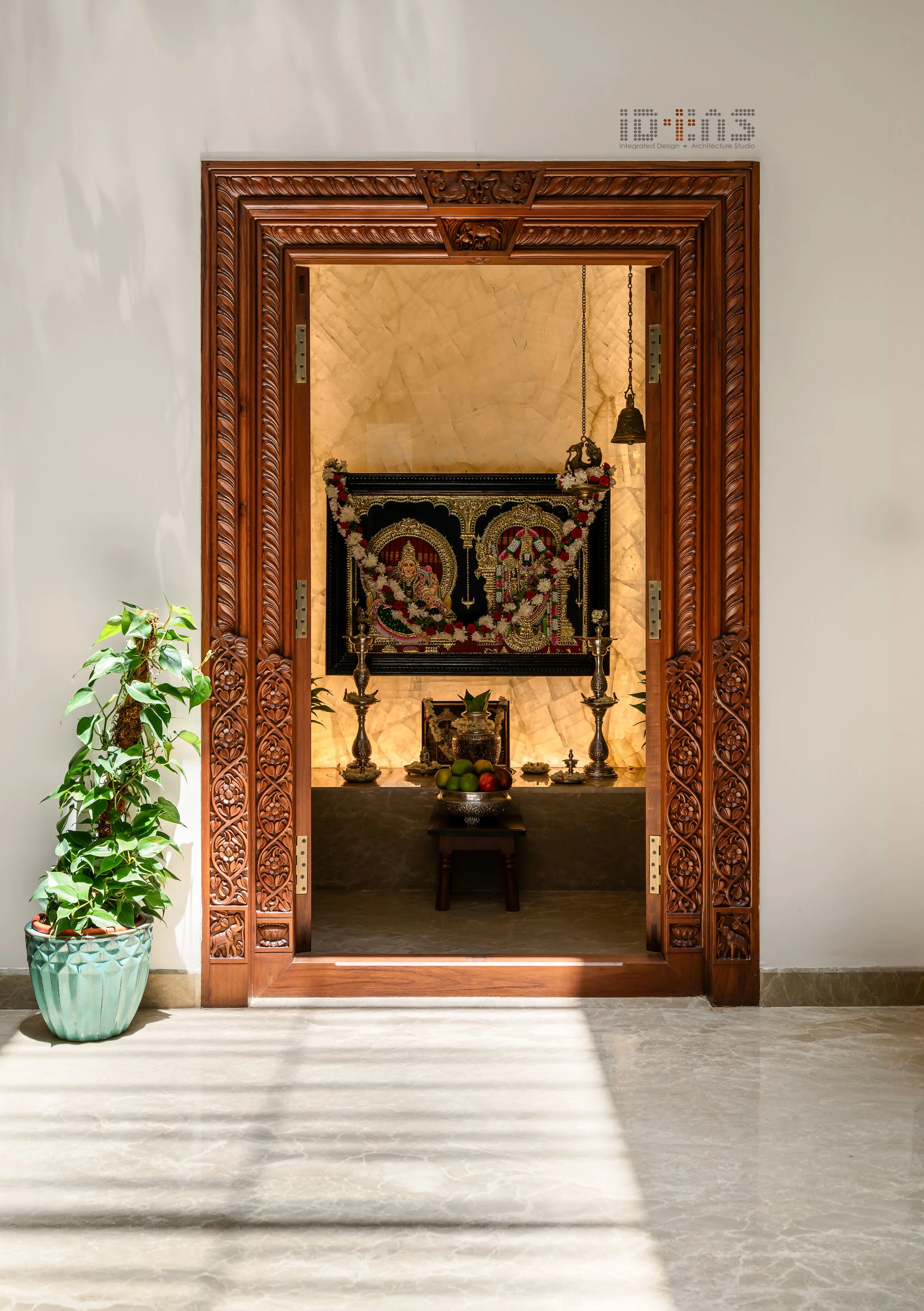 Pooja room behind the carved door, lit from above