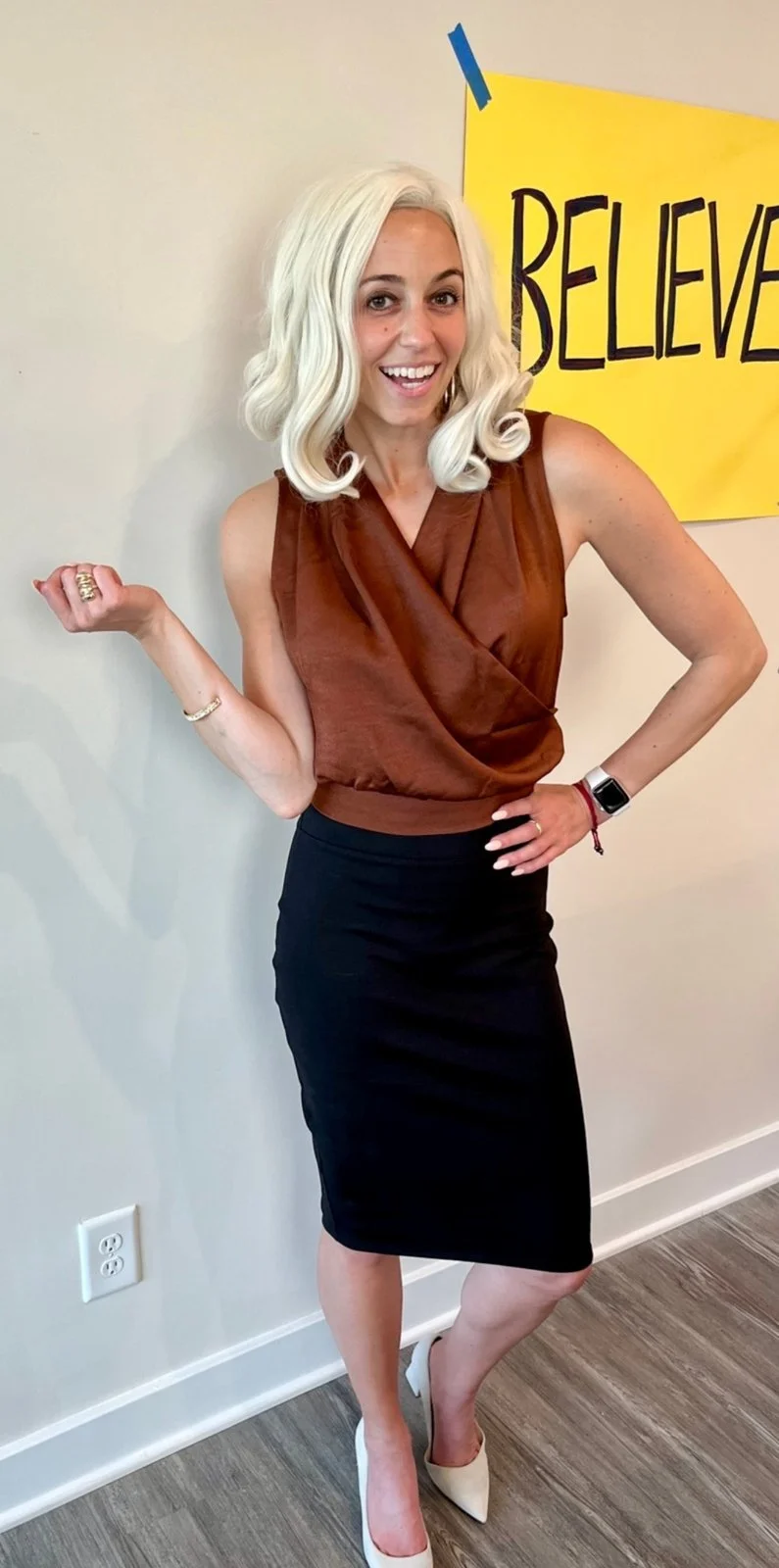 Lo Myrick dressed as Rebecca Welton from Ted Lasso in a rust satin top and black pencil skirt
