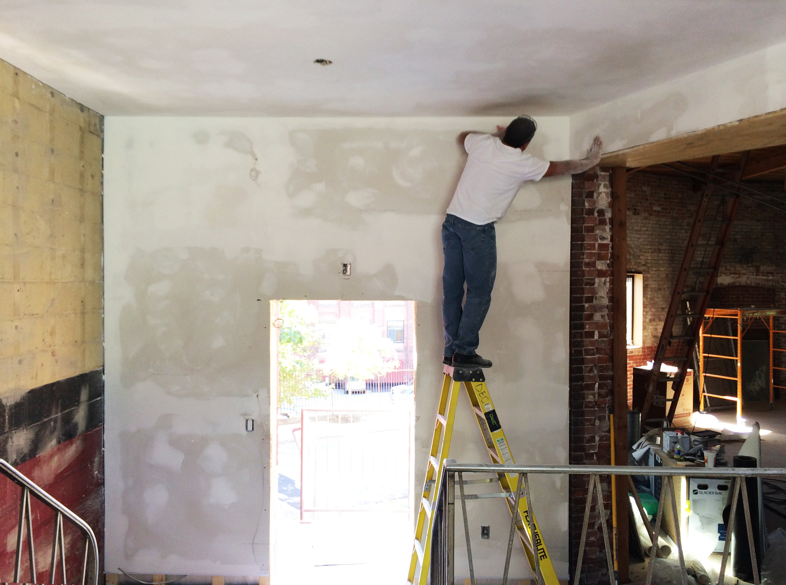 Ramon, doing something he shouldn't on a ladder, but working with craft to create a well finished wall regardless 