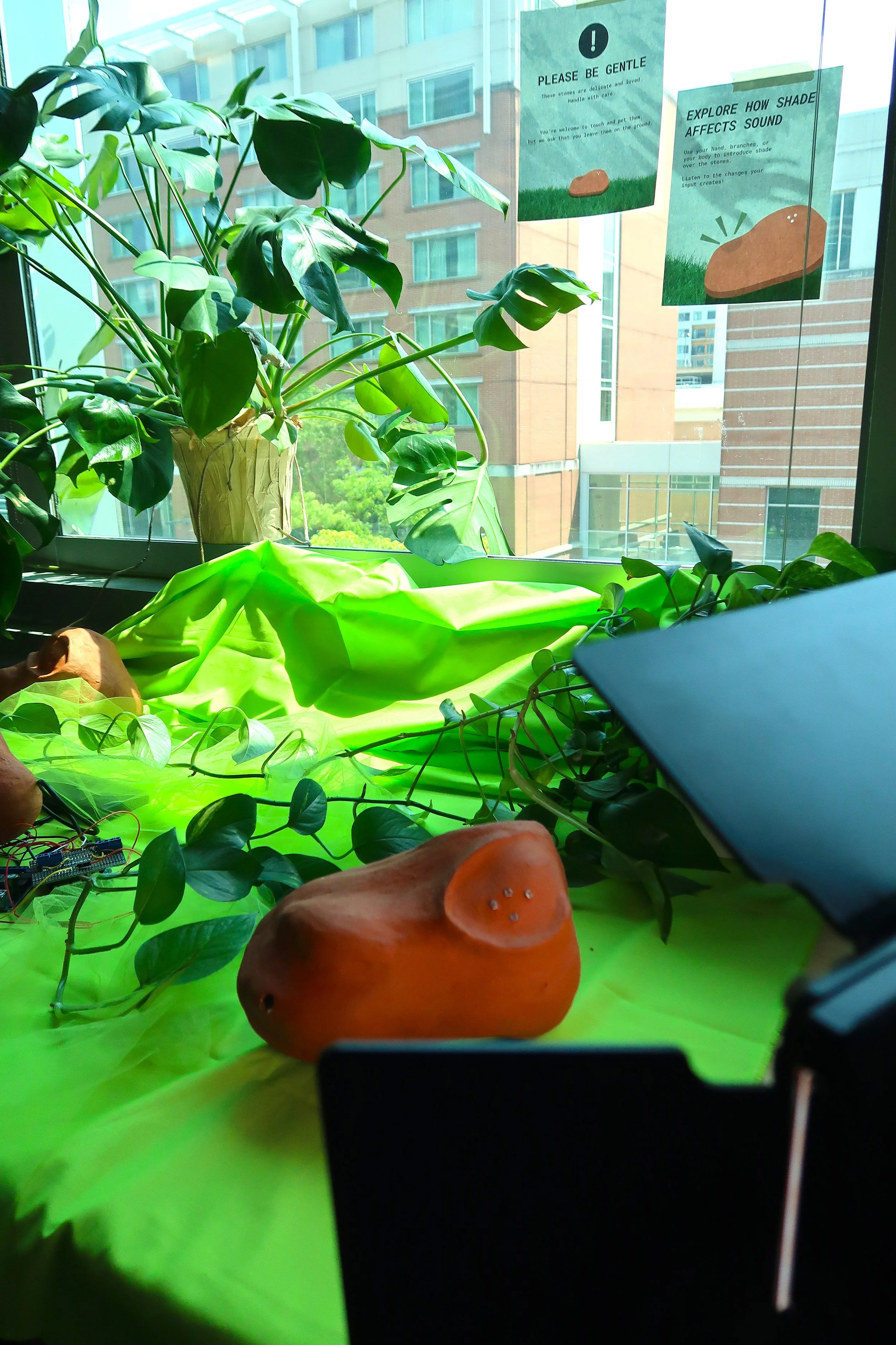 Photo of the Shade Synthesis installation exploring shade, light, and sound. The photo has a various plants, terracotta sculptures, and light sources. Photo: Pearl Kaplan/Tech Square ATL.