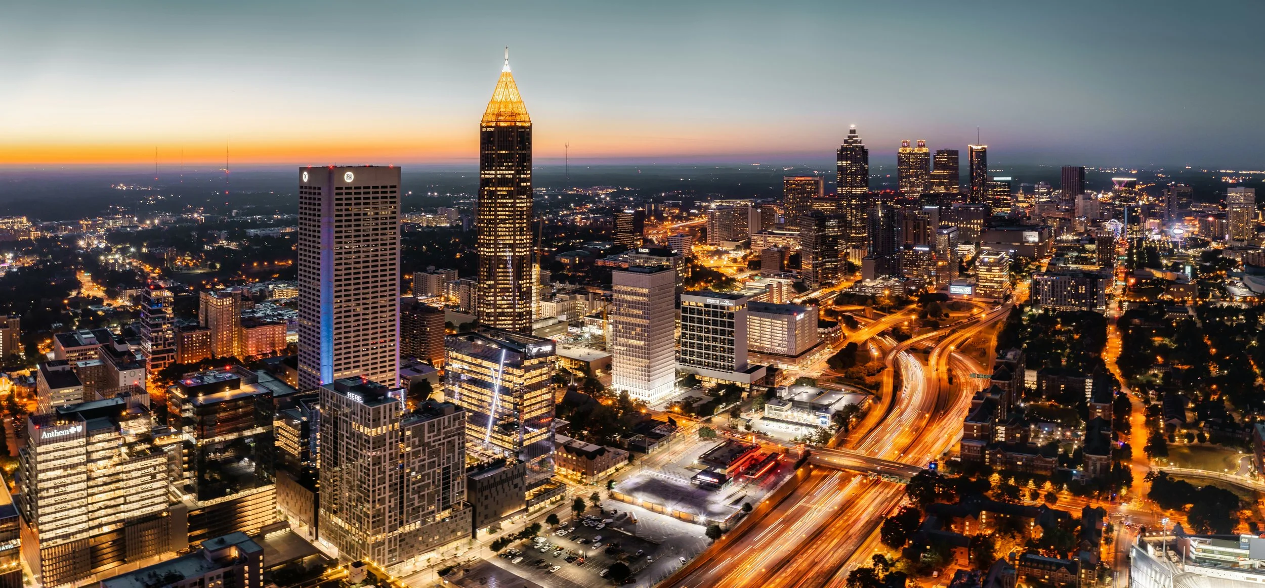 Stock photo of the City of Atlanta skyline at night with city building lights and car headlights on roads. Source: Venti Views/Unsplash.