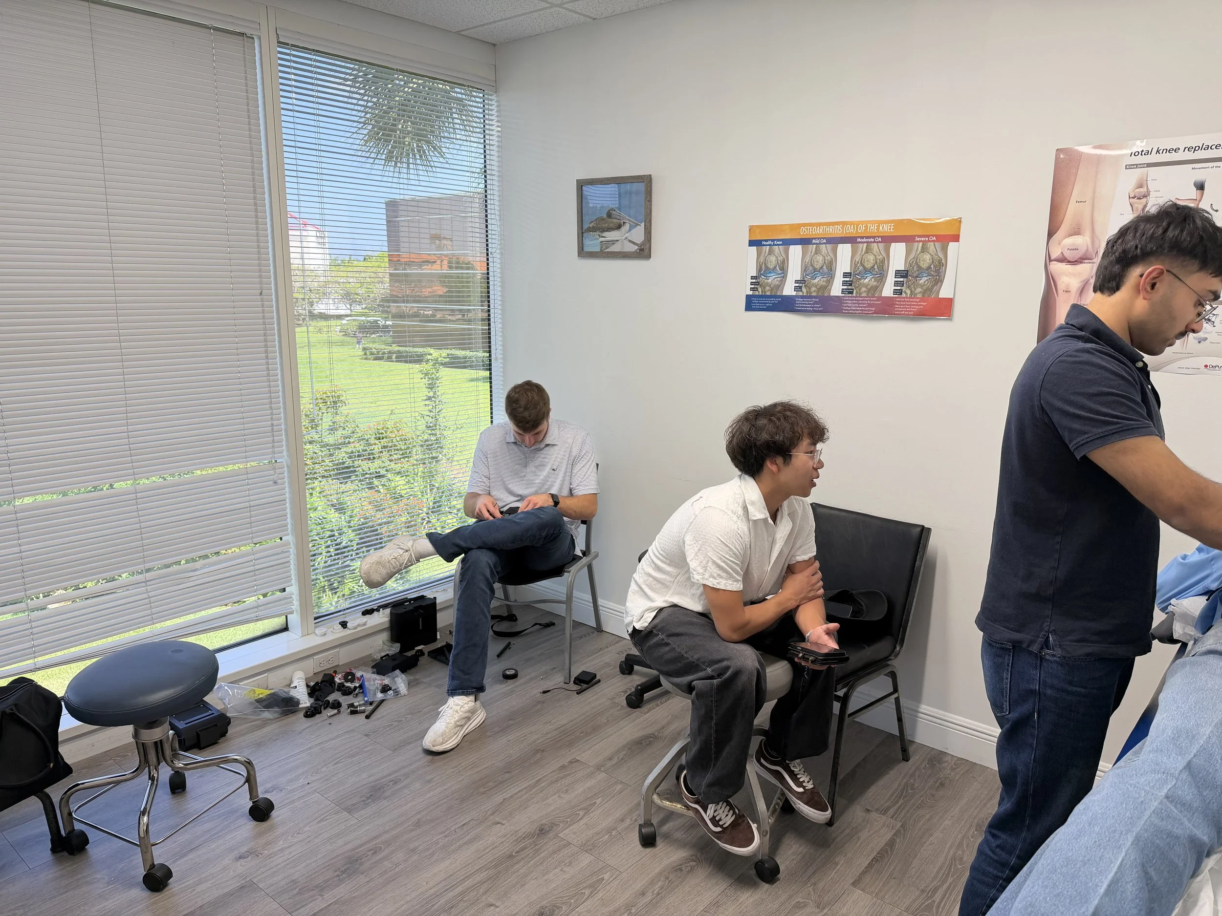 Photo of the IASTMotion team testing device functionality, building prototypes, and troubleshooting while visiting a physical therapy clinic. Source: IASTMotion.