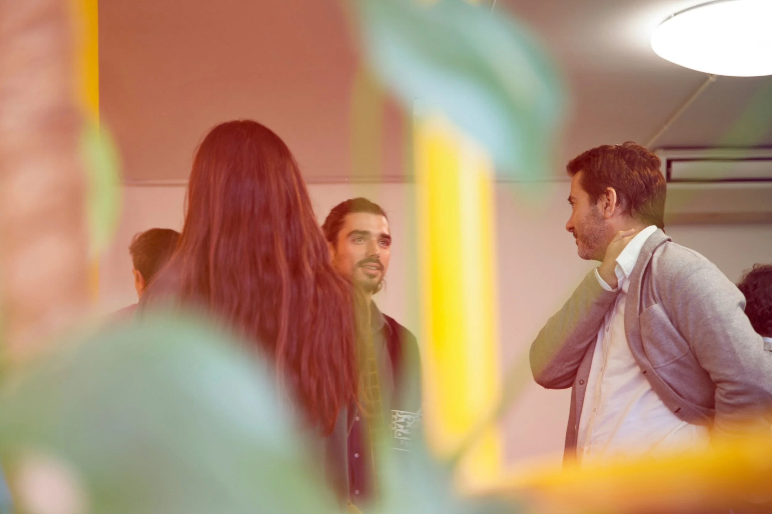 Stock photo of several people talking at a business networking event. There is a soft overlay of teal and yellow blurred over the image. Source: Hivan Arvizu Soyhivan/Unsplash.