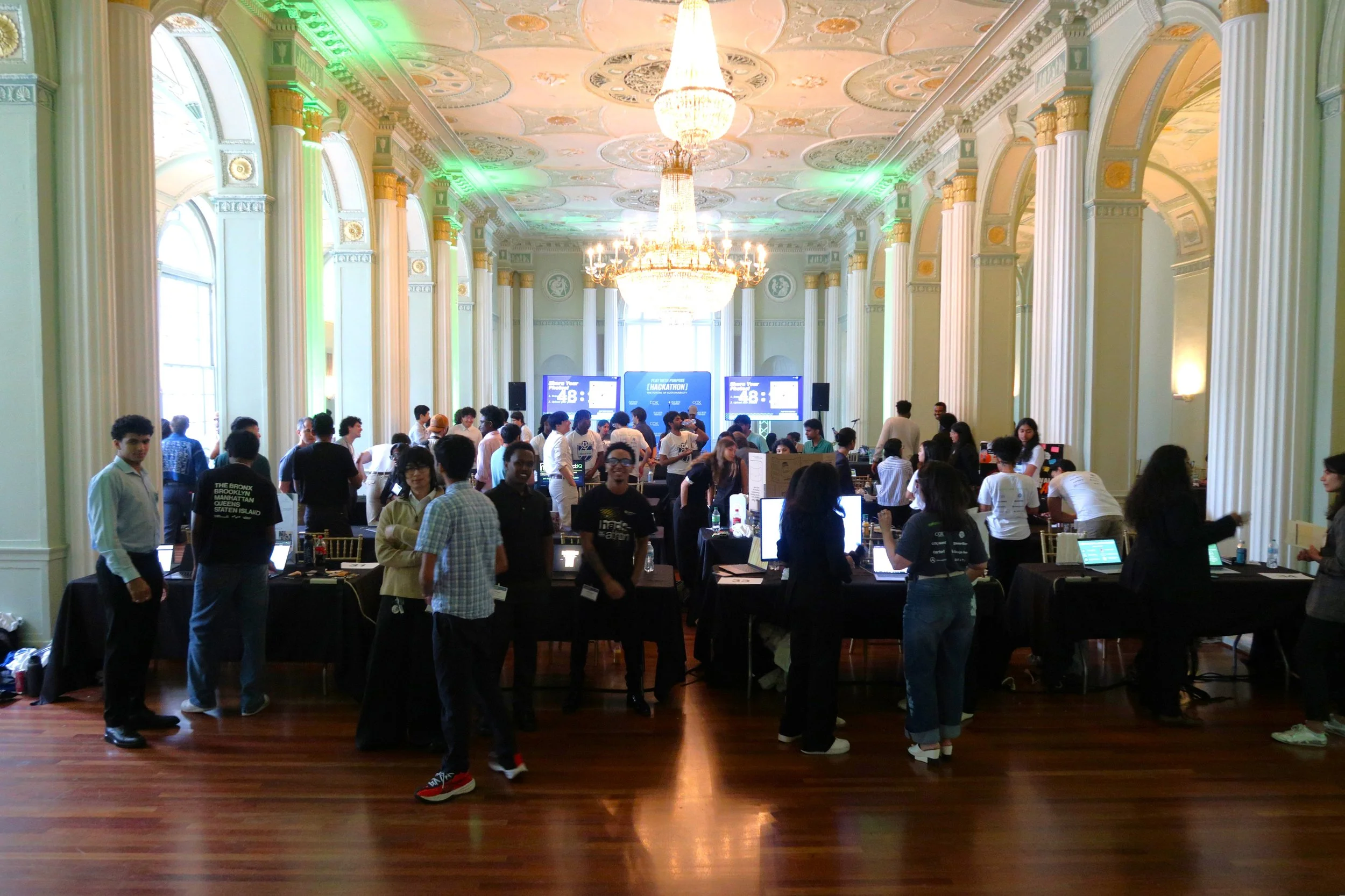 Photo of the Biltmore Innovation Center ballroom filled with students, innovations, judges, computer screens, and artifacts on display at the hackathon showcase. Source: Pearl Kaplan/Tech Square ATL.