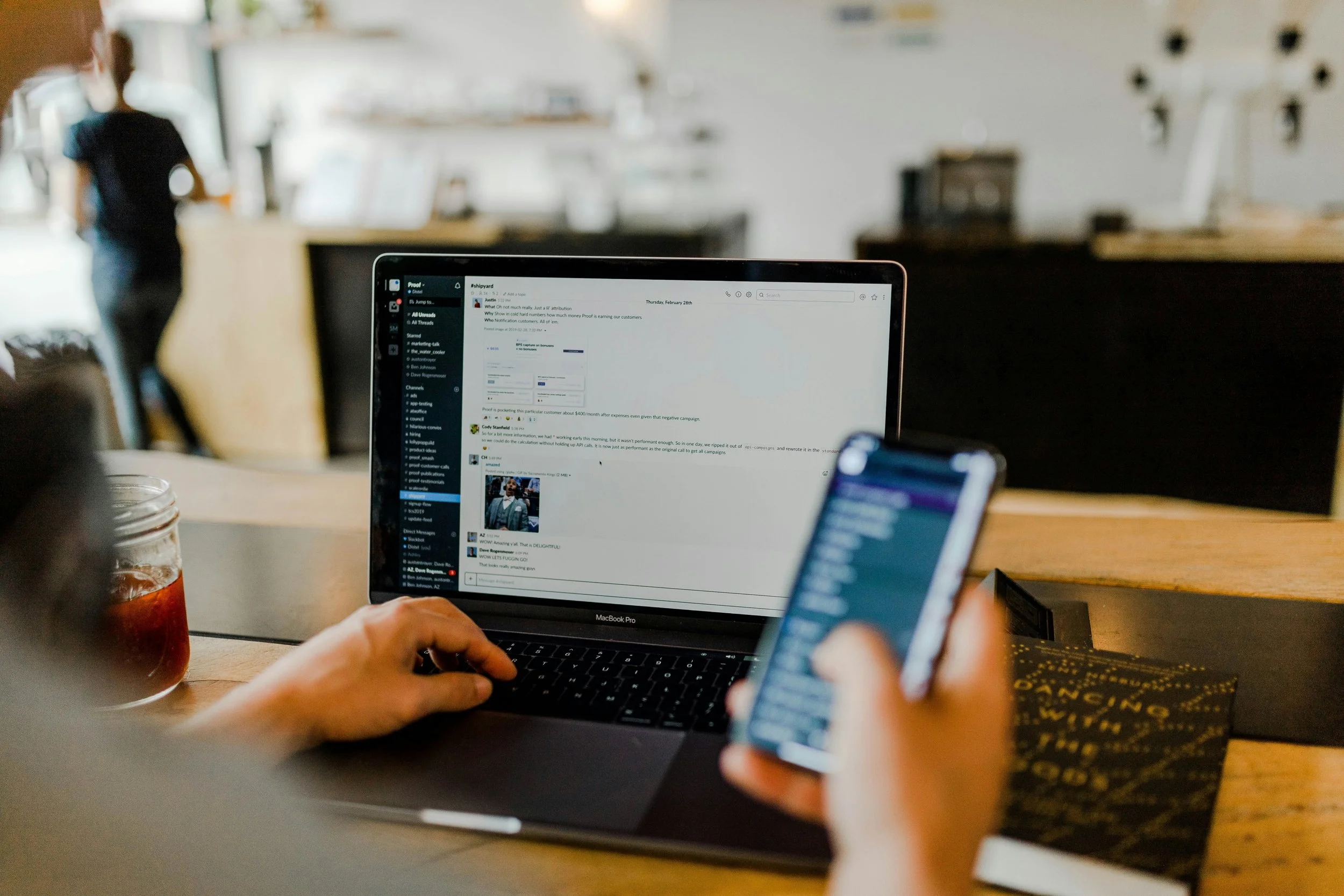 Stock photo of a person sitting in front of a computer screen and mobile phone.