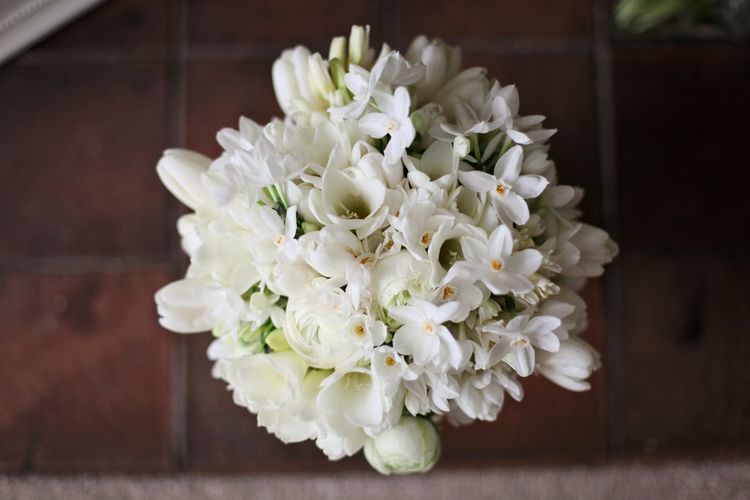 All white spring wedding bouquet with ranuncula, freesia, and narcissi.