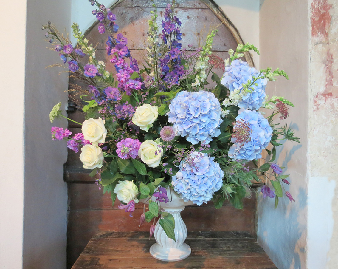 Wedding display with tall purple delphinium and blue hydrangea.