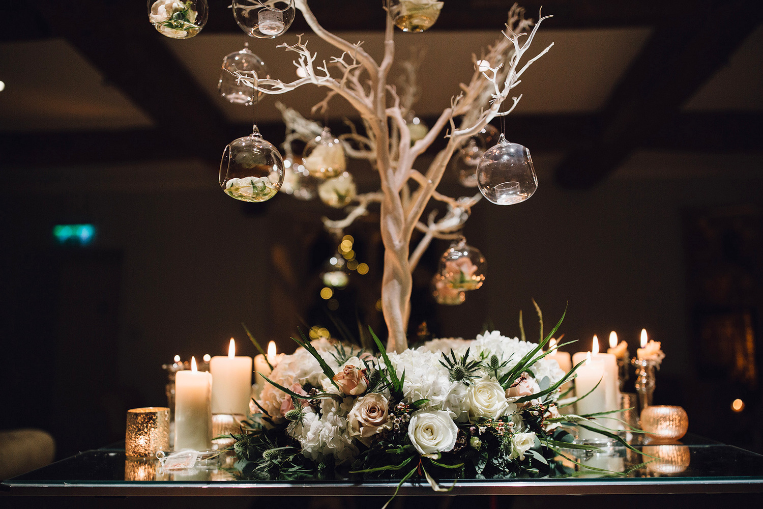 Christmas wedding centrepiece with manzanita tree, floral base & glass baubles at Notley Abbey Bucks
