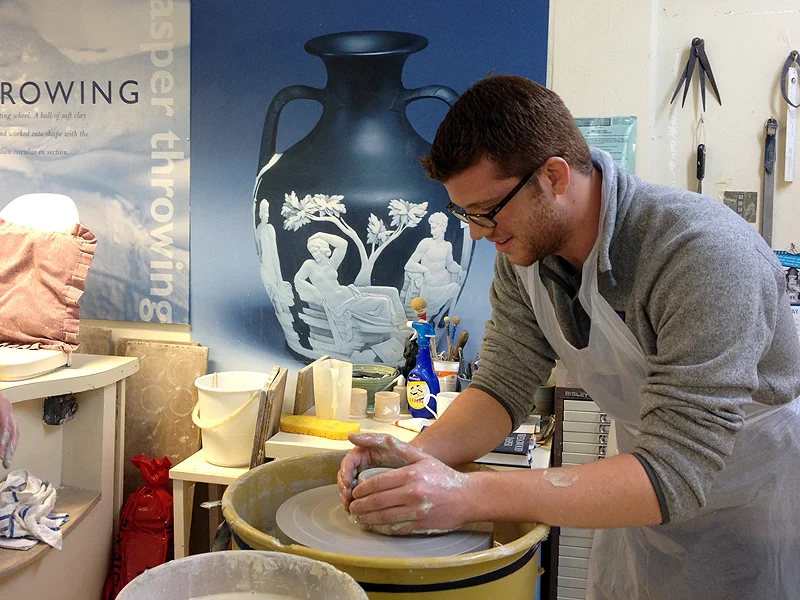 Joe Chemello learning how to throw a pot with the artisans at Wedgewood Pottery.