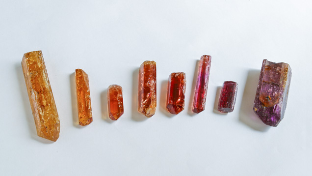 Topaz crystals are typically elongated, with grooves parallel to their lengths. For this reason, they're commonly cut into long oval or pear shapes. These crystals show orange, pink, and brown colors. - Eric Welch/GIA