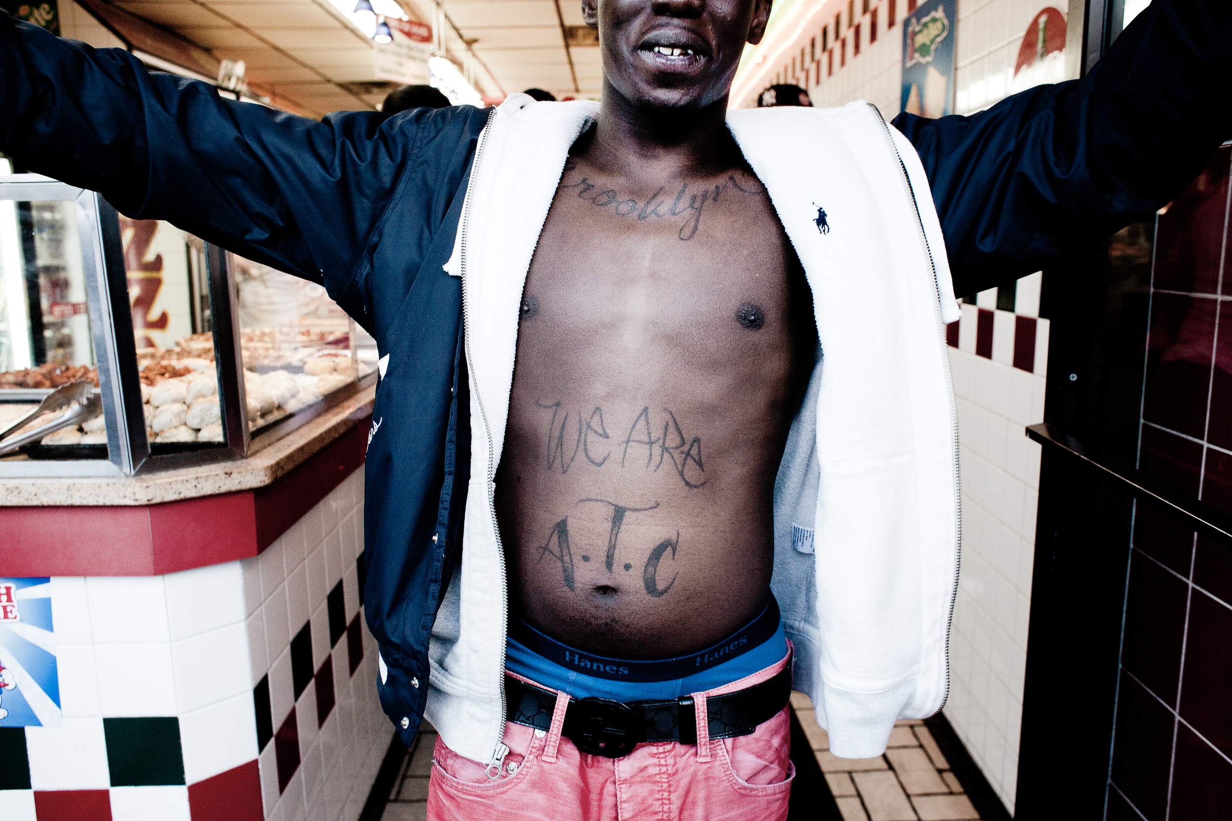 A young man shows off his Addicted To Cash tattoo, 2013.