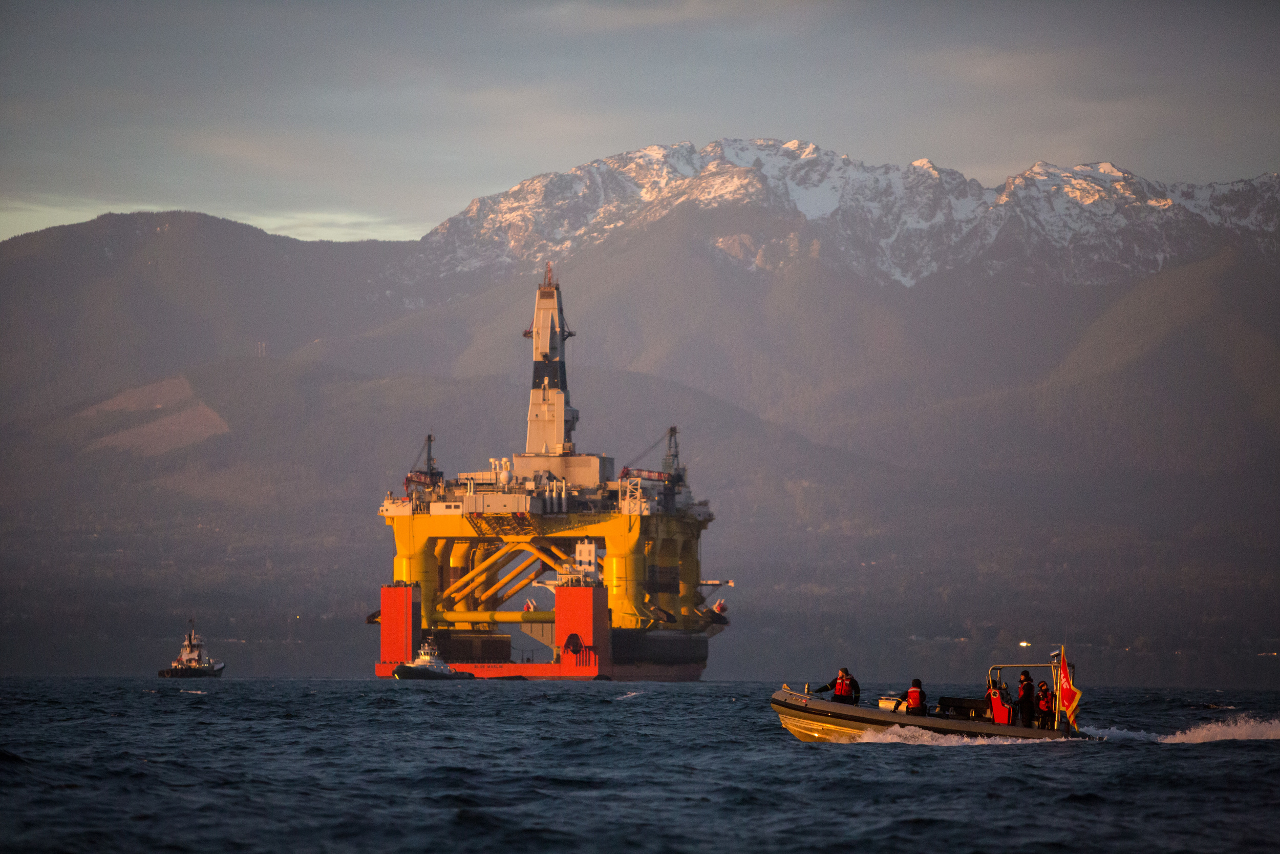   With the Olympic Mountains in the background, a Greenpeace boat crosses in front of the Transocean Polar Pioneer as it arrives in Port Angeles, Washington on its way to Seattle. The rig arrived aboard a transport ship after traveling across the Pac
