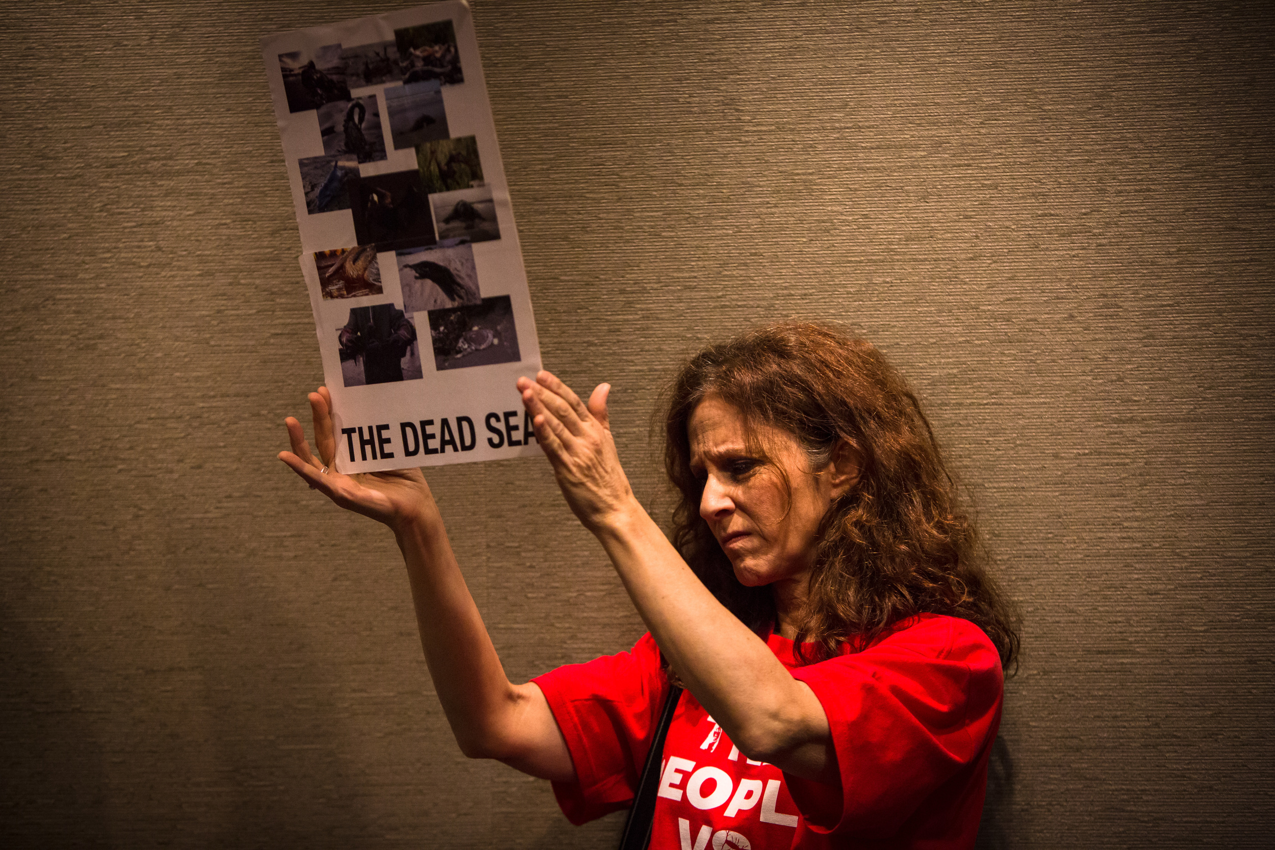   Marla Katz holds up a photos from the BP oil spill in protest of Shell's oil rig coming to Seattle during a meeting at the Port of Seattle on Tuesday, May 12, 2015. Members of the community packed in to speak to the Port Commissioners before they v