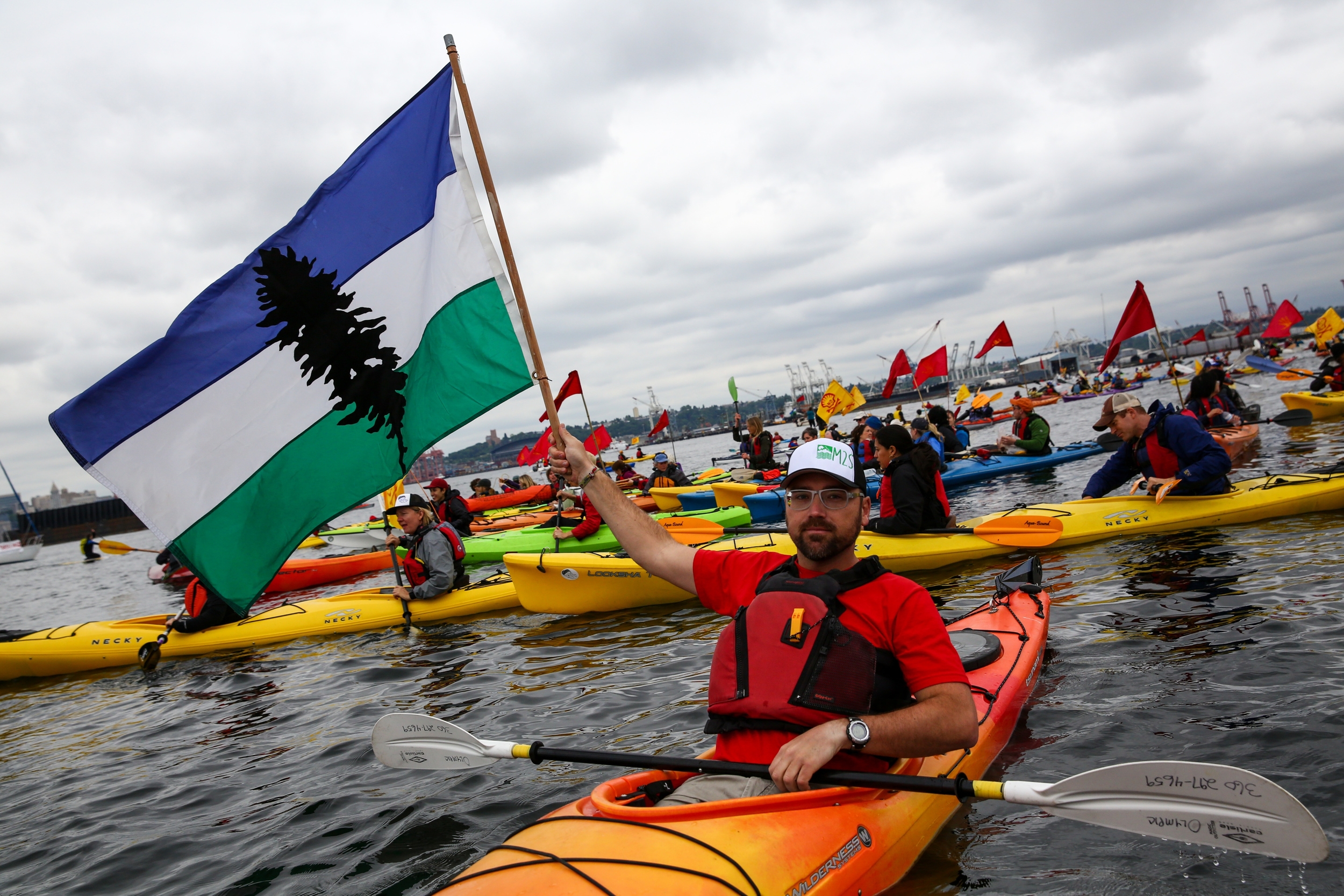   A man holds up a Cascadian flag as hundreds of kayaktivists take to the water during protest against drilling in the Arctic and the Port of Seattle being used as a port for the Shell Oil drilling rig Polar Pioneer. The protest flotilla drew many pa