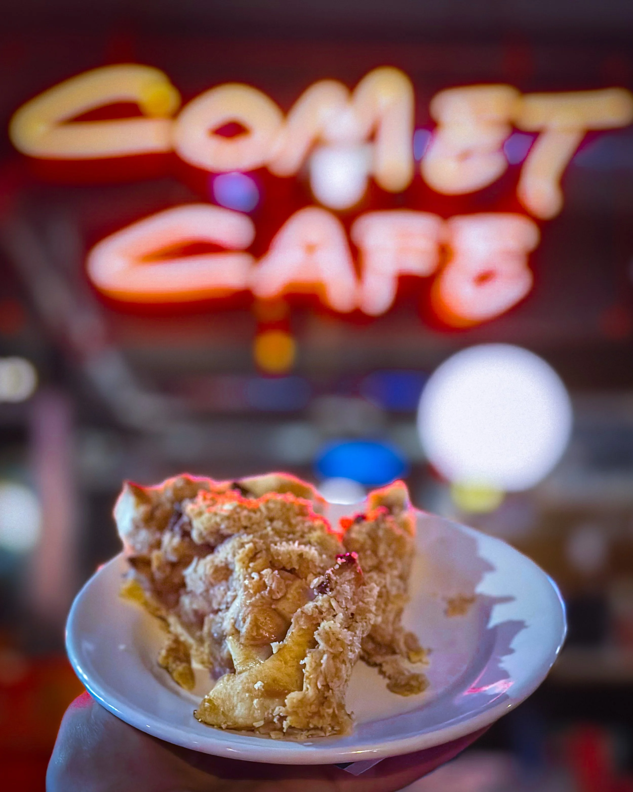 Apple pie on a white plate in front of the Comet Cafe.